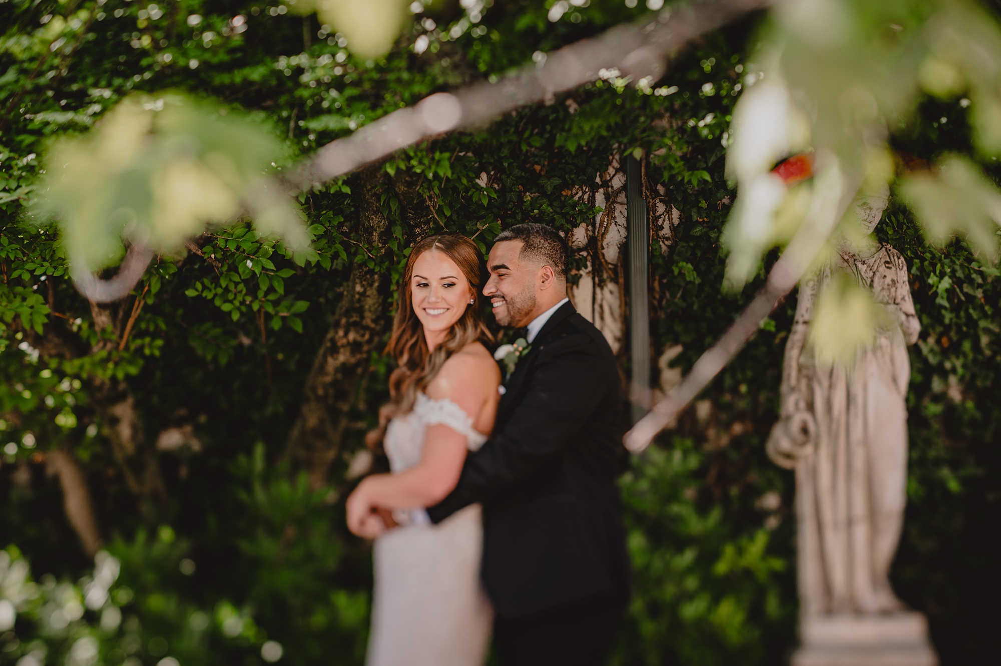groom hugs bride from behind under arbor at David's Country Inn