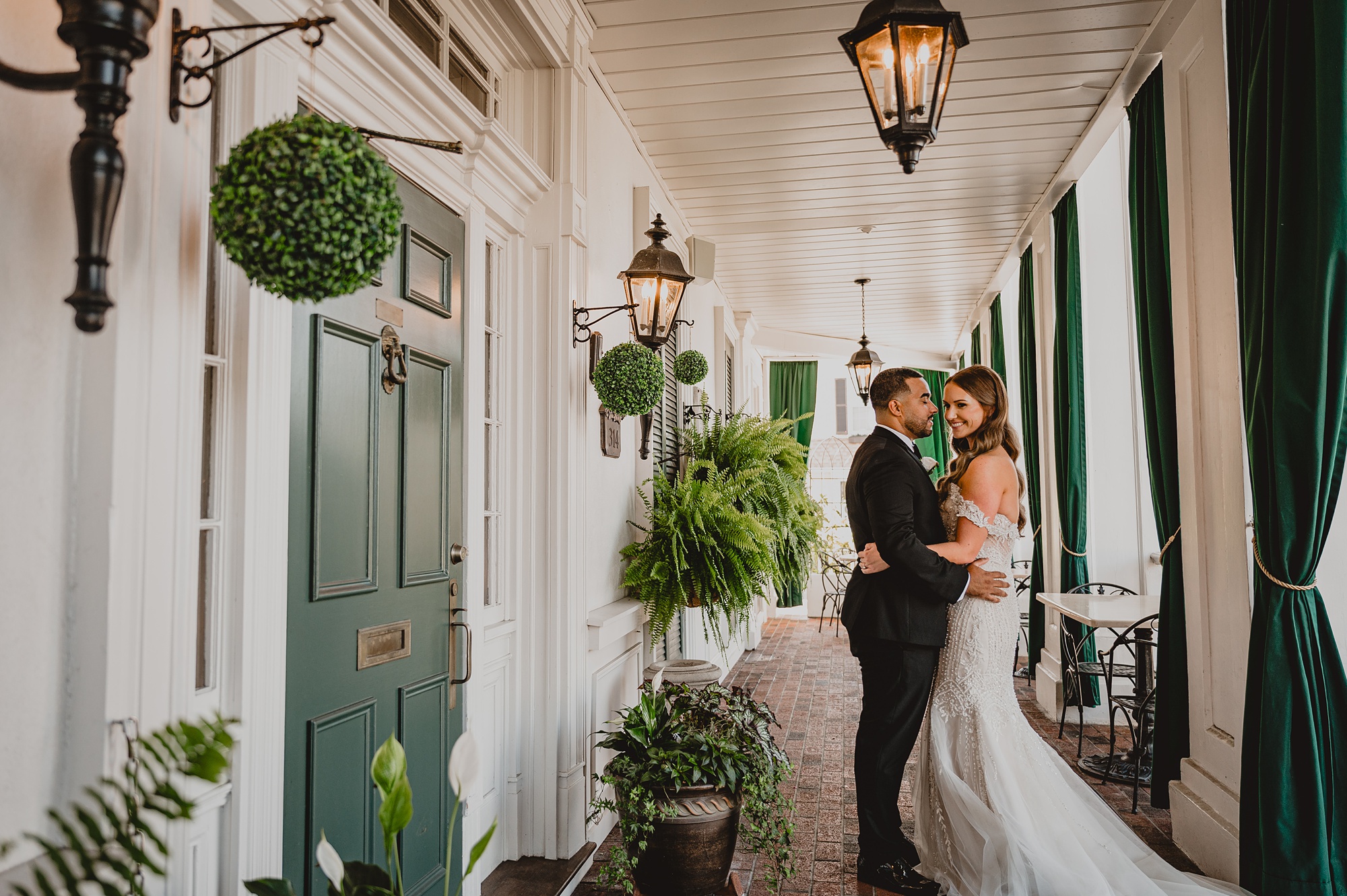 newlyweds pose in front of green doors and window shutters