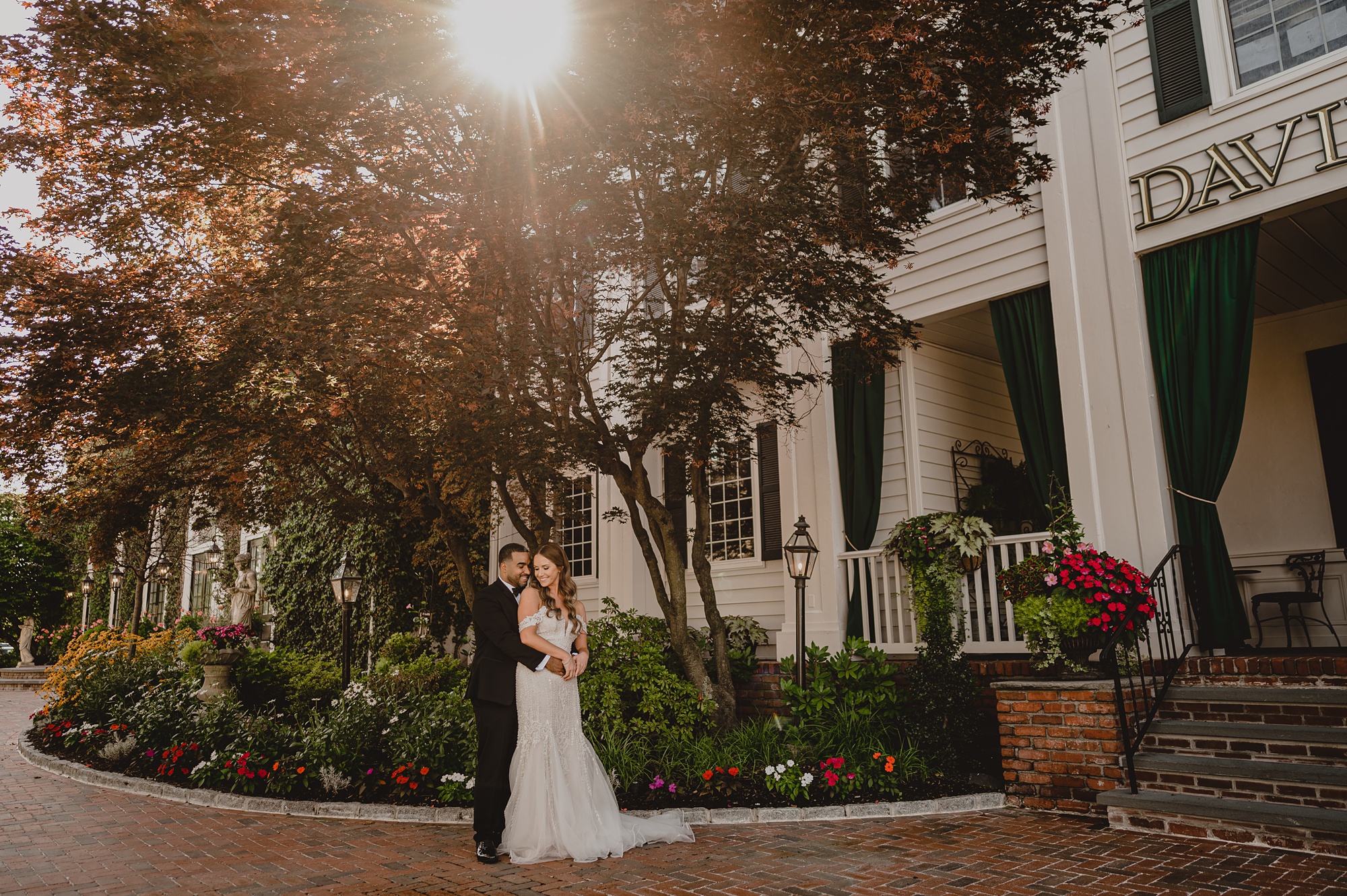 groom hugs bride in front of tree outside David's Country Inn