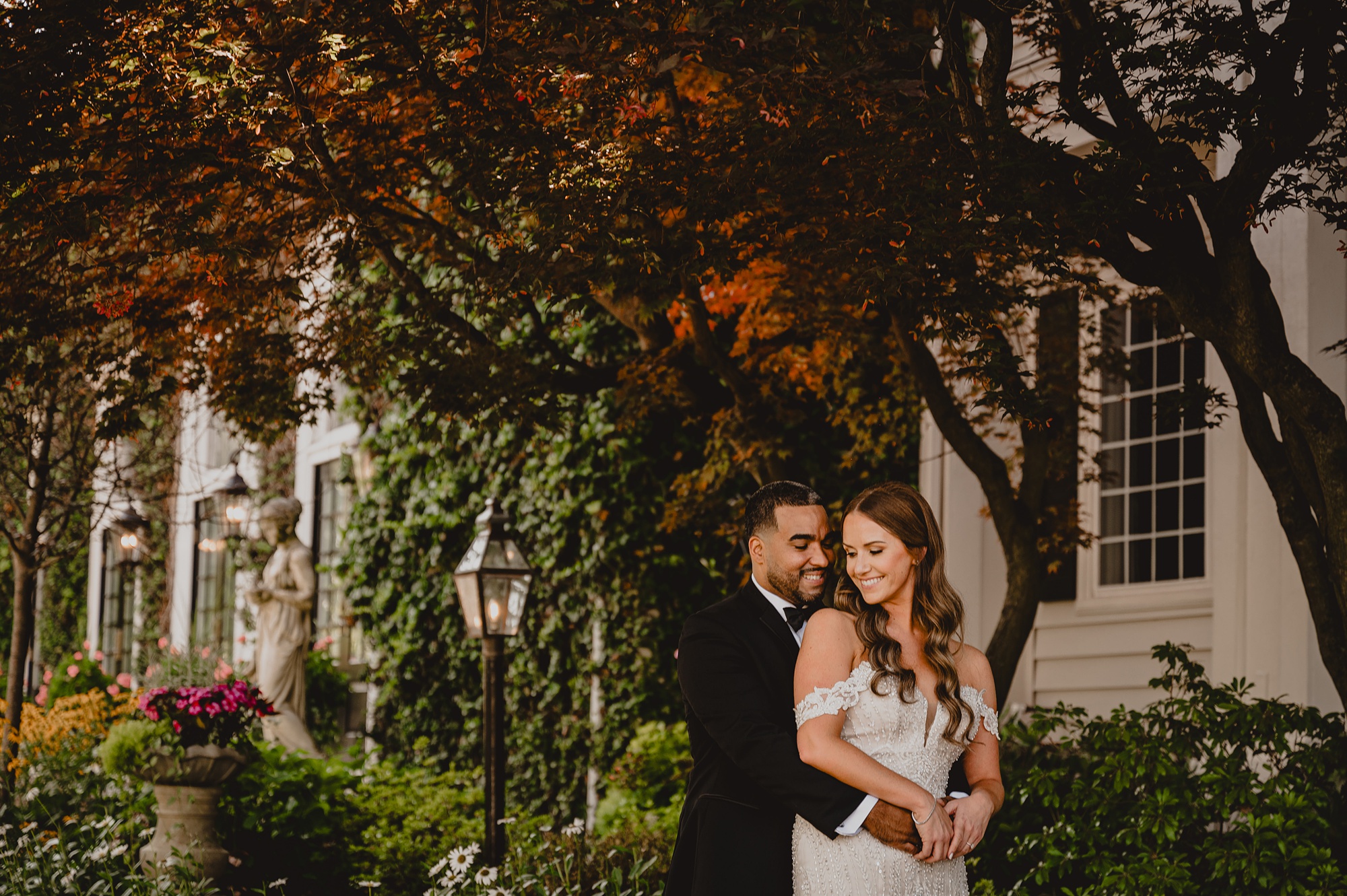 newlyweds hug in front of red leaves of trees at David's Country Inn