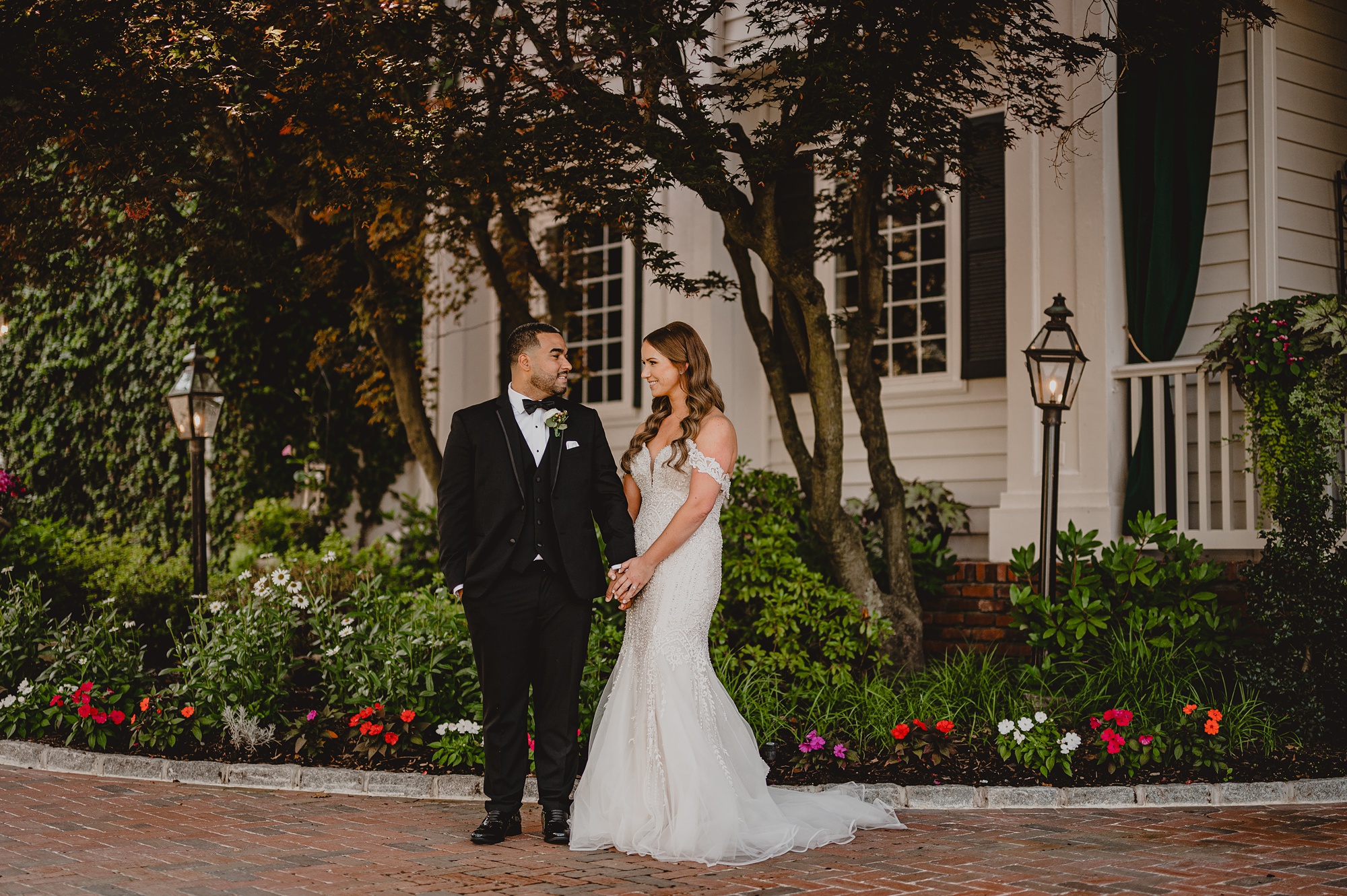 bride and groom smile in front gardens in New Jersey