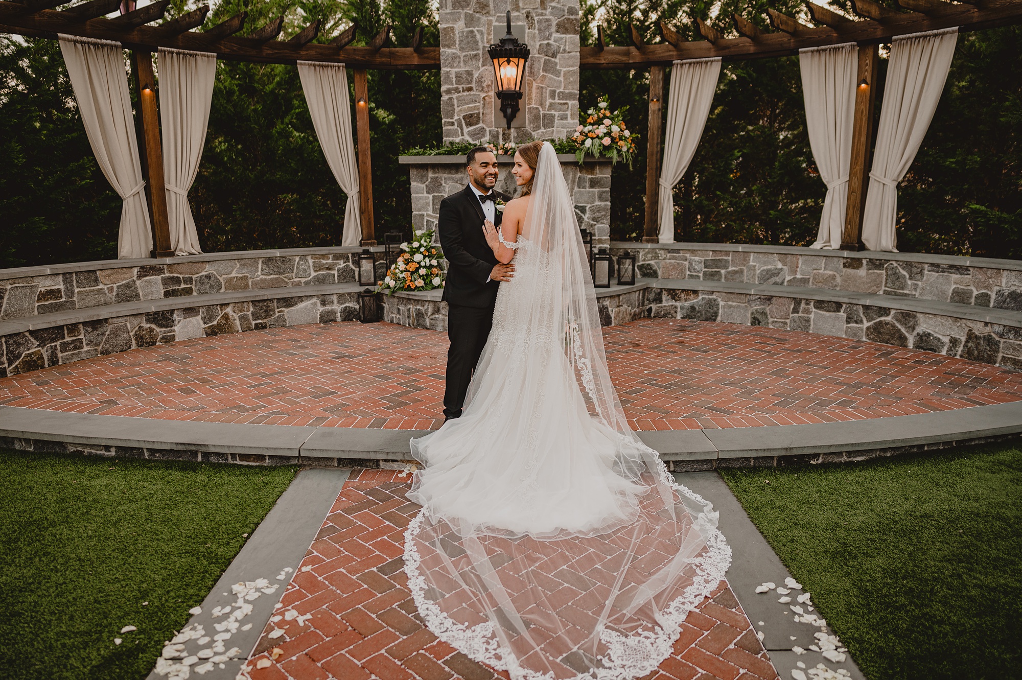 bride and groom pose in front of brick patio