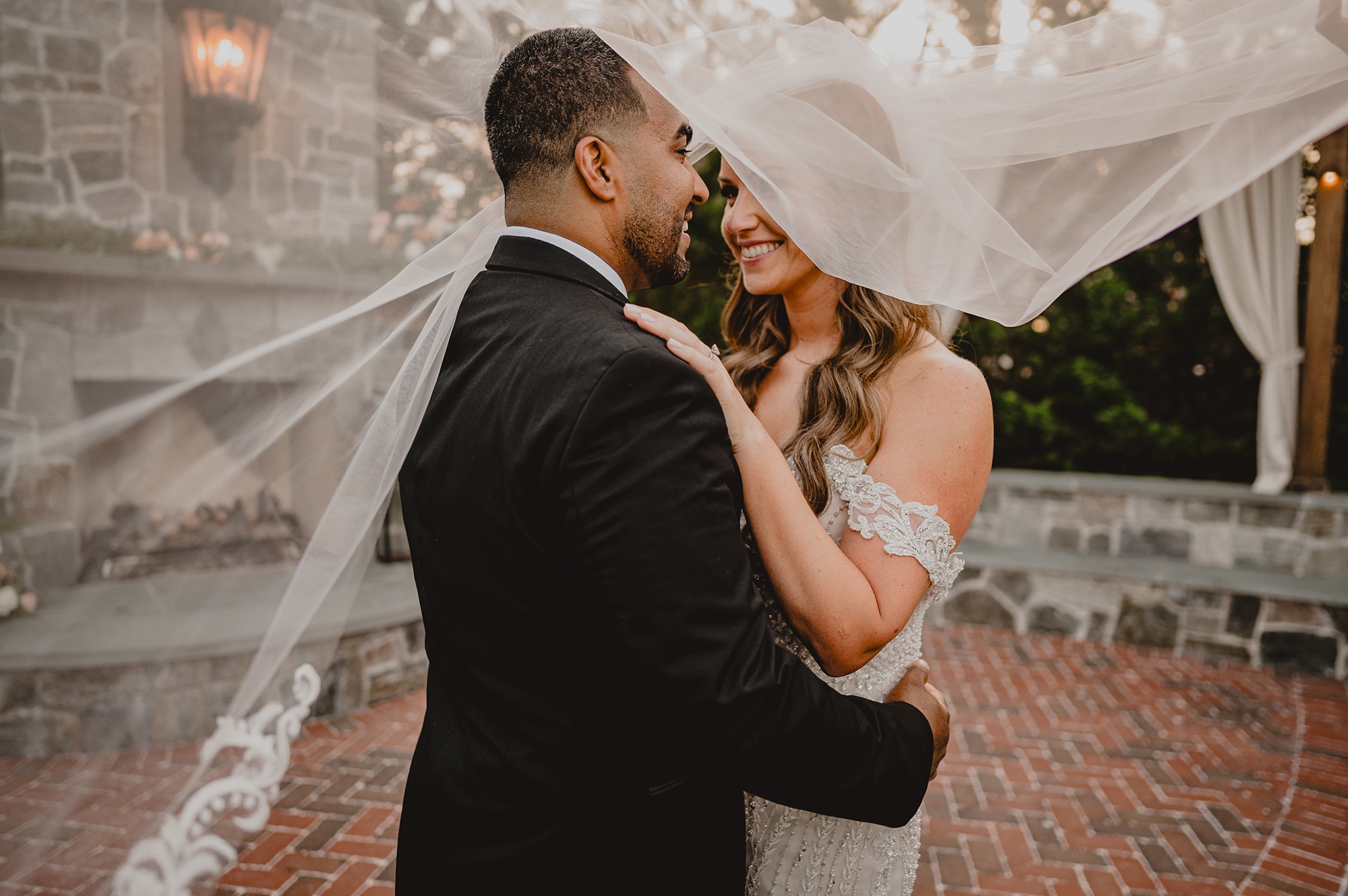 bride and groom hug under veil during wedding day