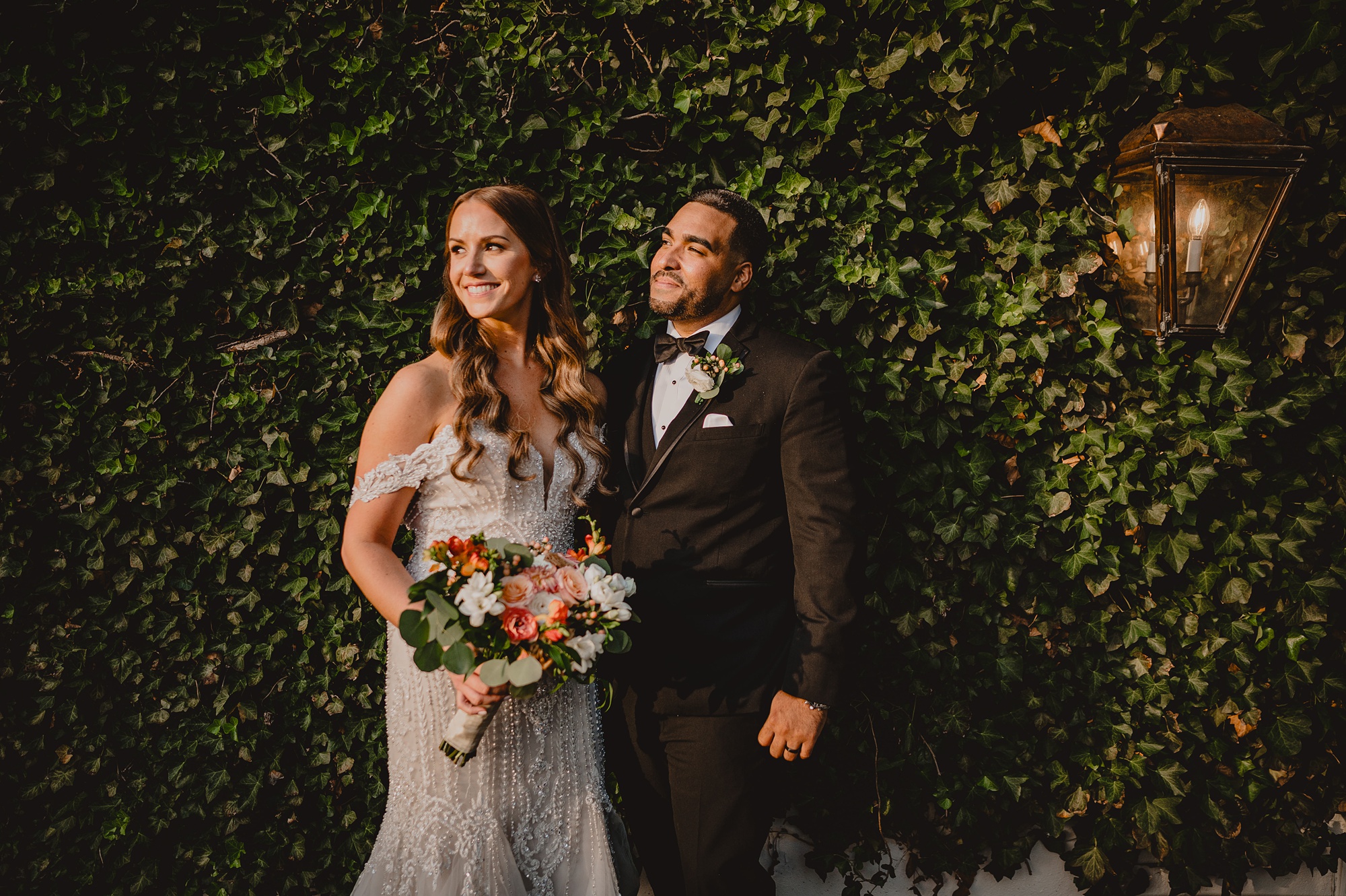 bride and groom hug in front of ivy covered wall during portraits at David's Country Inn