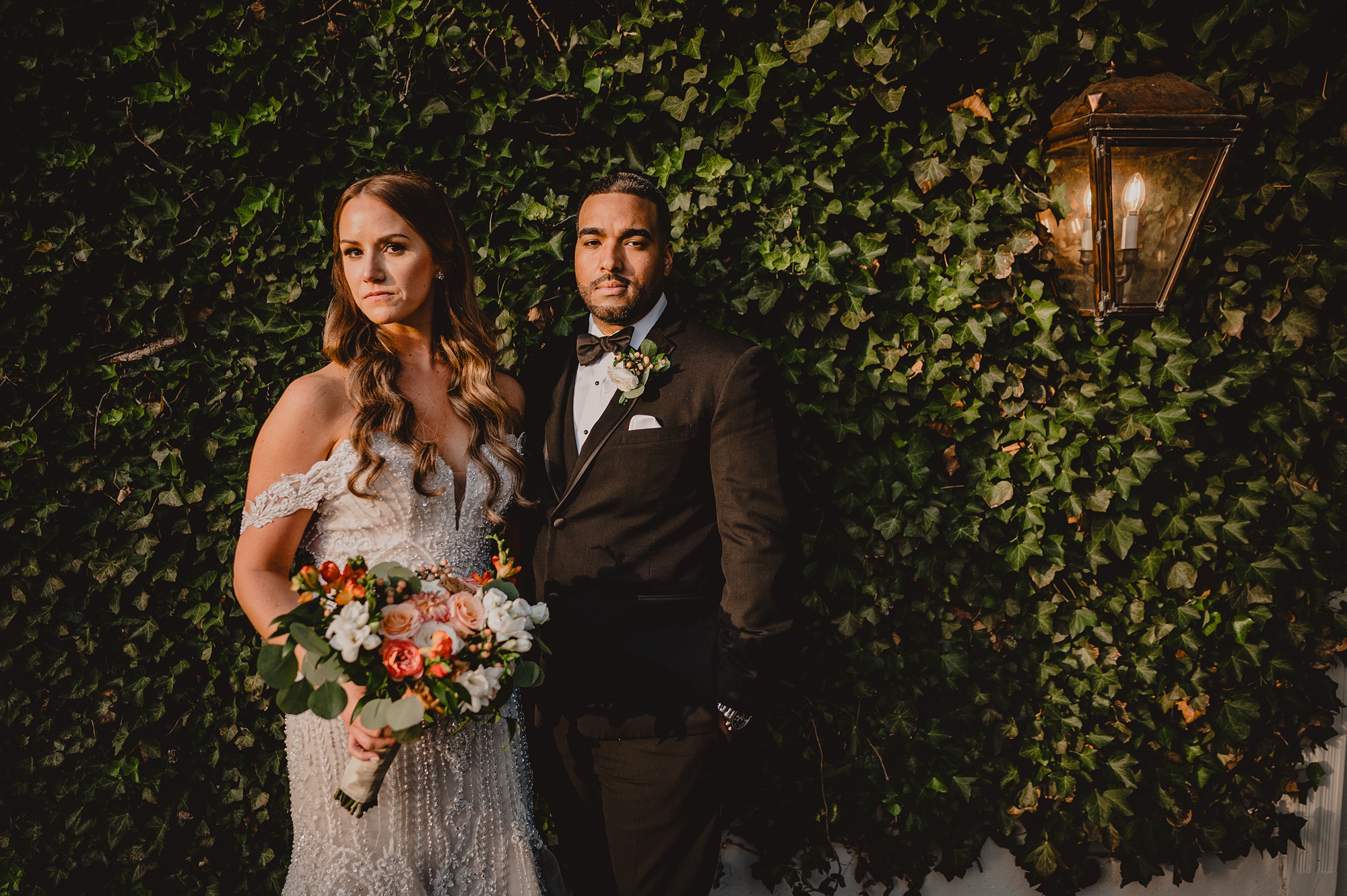 bride and groom hug in front of ivy covered wall during portraits at David's Country Inn