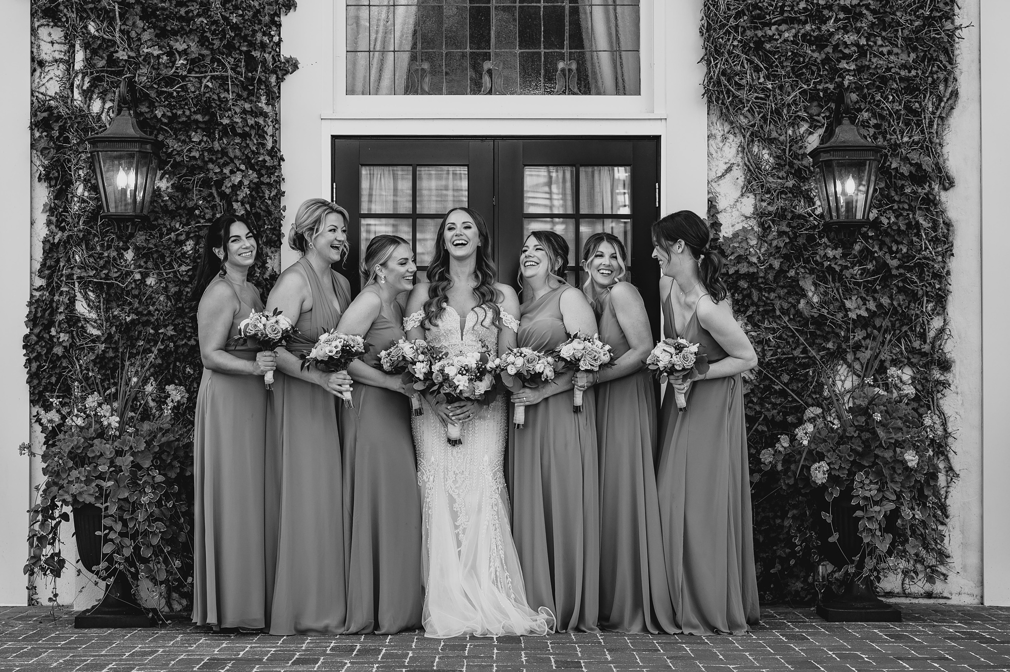 bride and bridesmaids smile in front of glass doors at David's Country Inn