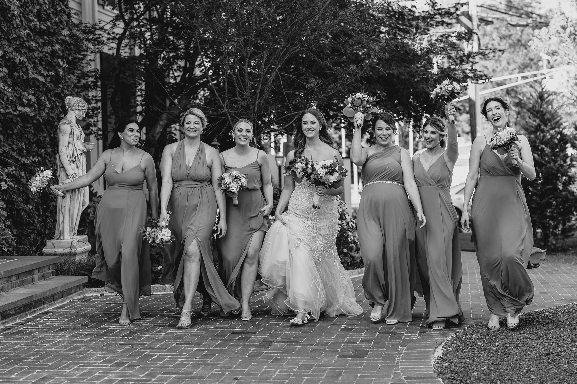 bride walks with bridesmaids on brick walkway