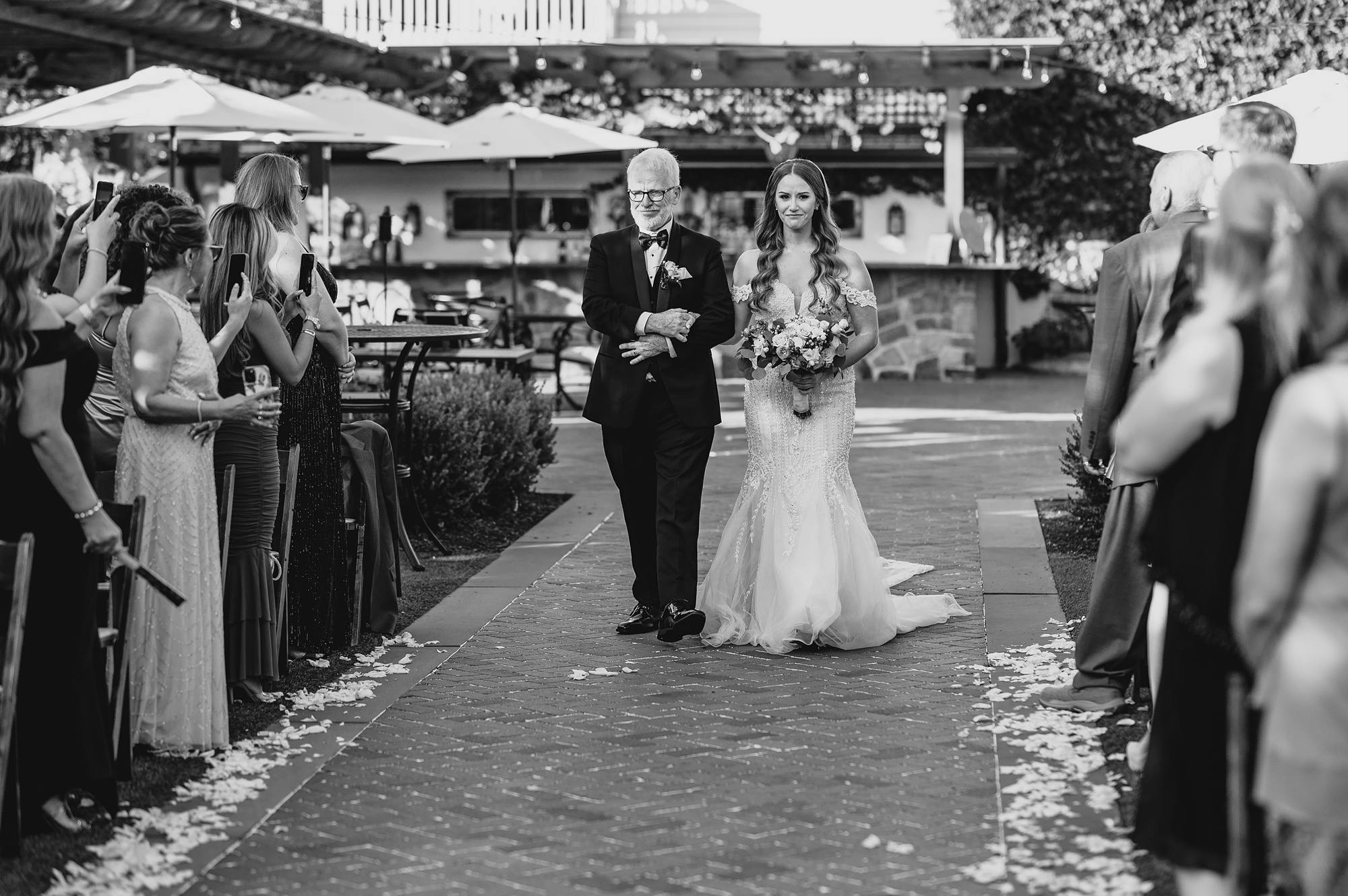 father walks bride down aisle for wedding ceremony on brick patio at David's Country Inn