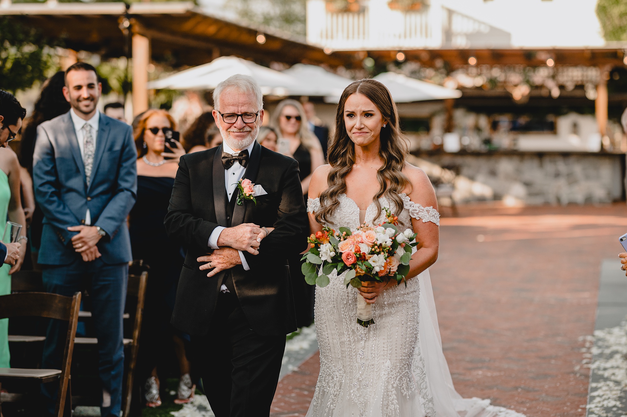 bride and dad walk down aisle for wedding ceremony on brick patio at David's Country Inn