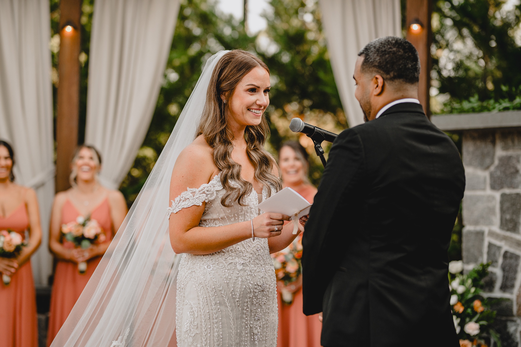 bride smiles at groom during wedding ceremony on brick patio at David's Country Inn