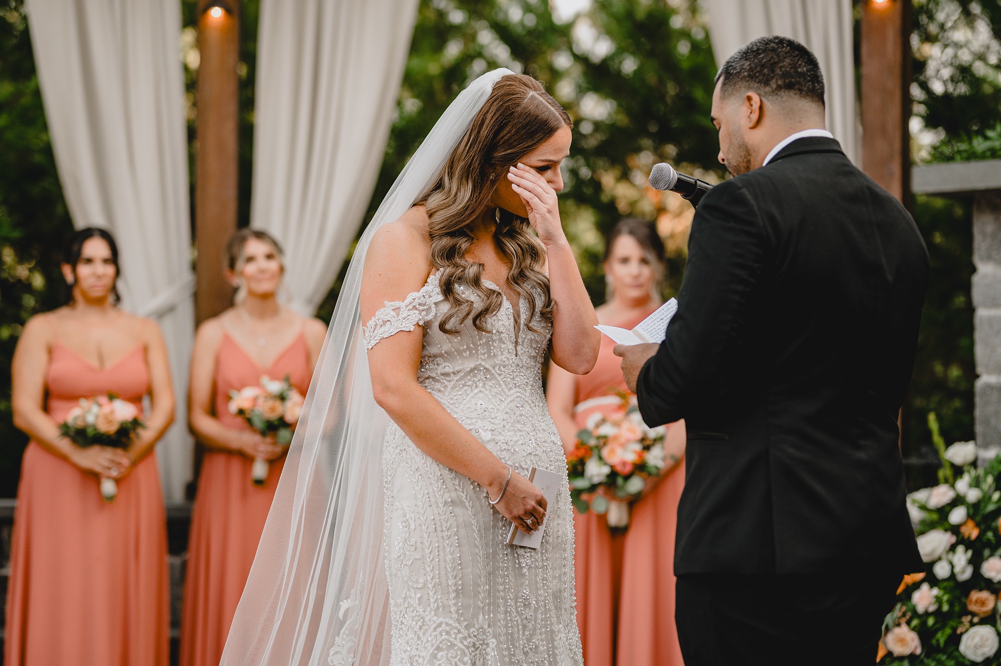 bride wipes eyes during wedding ceremony on brick patio at David's Country Inn