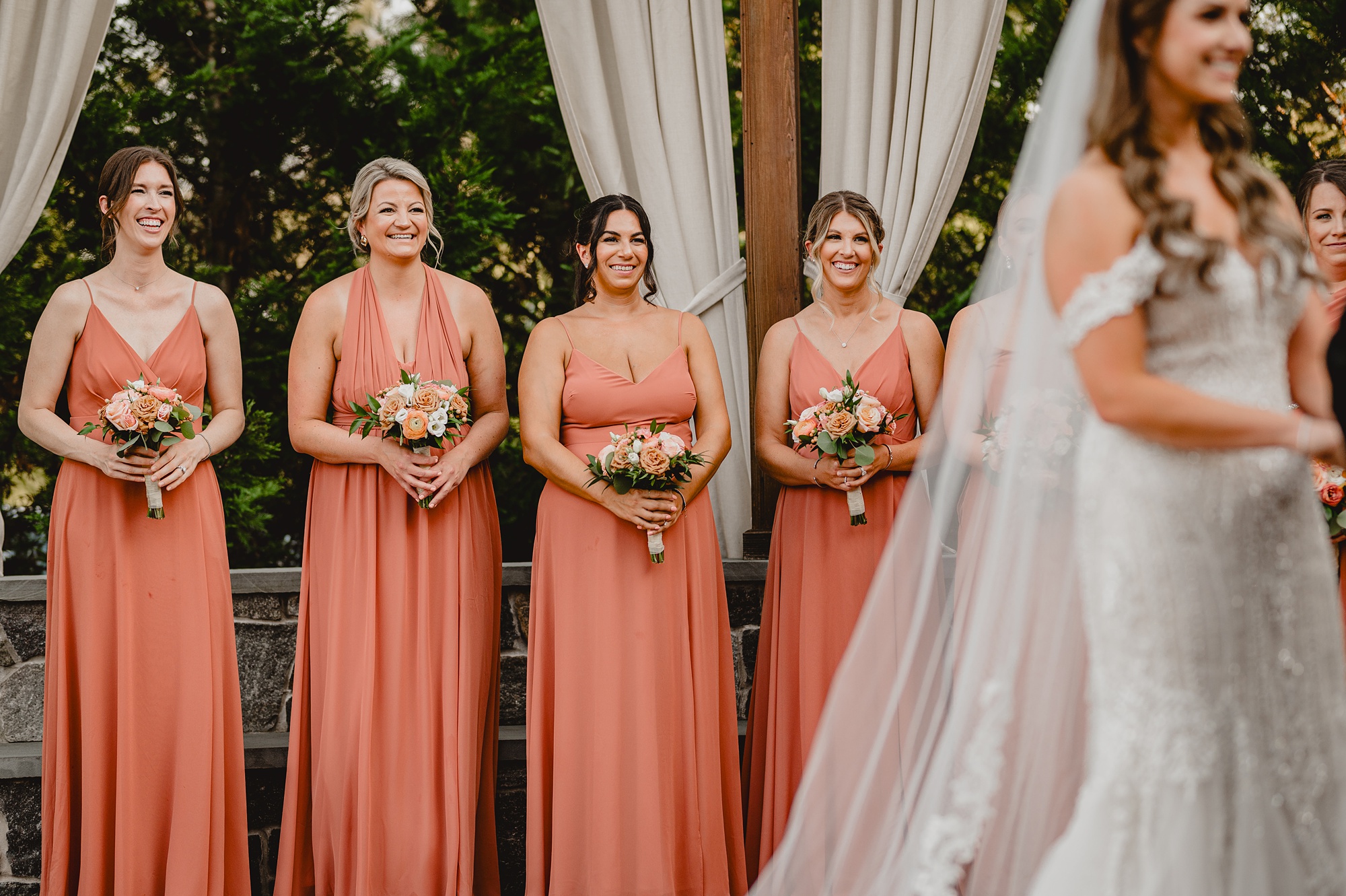 bridesmaids in salmon pink watch wedding ceremony on brick patio at David's Country Inn