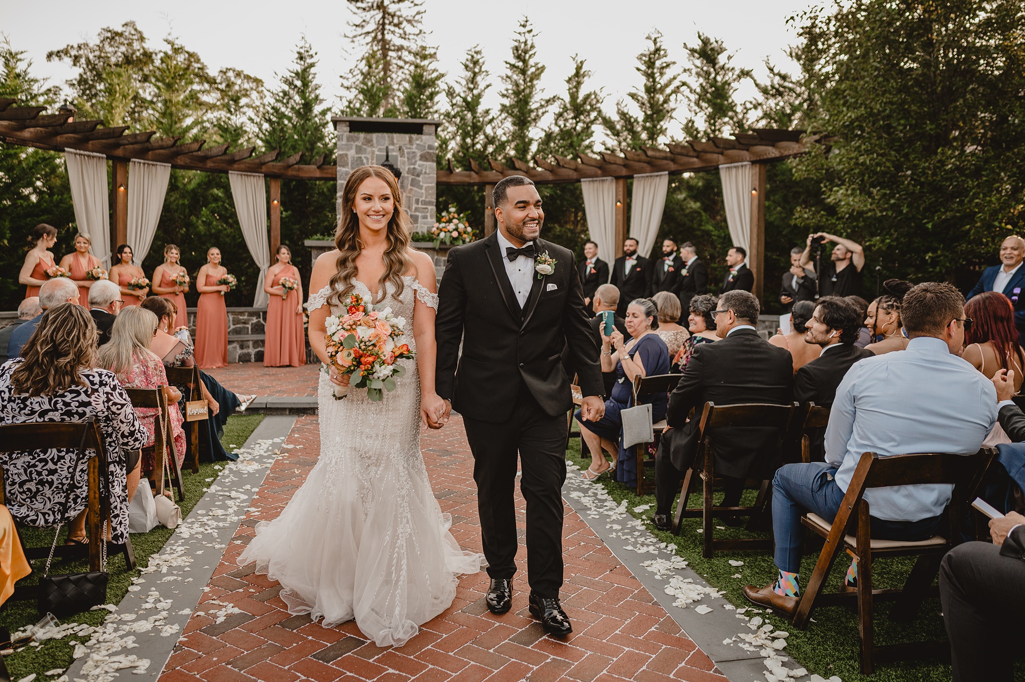 newlyweds hold hands walking up aisle after wedding ceremony on brick patio at David's Country Inn