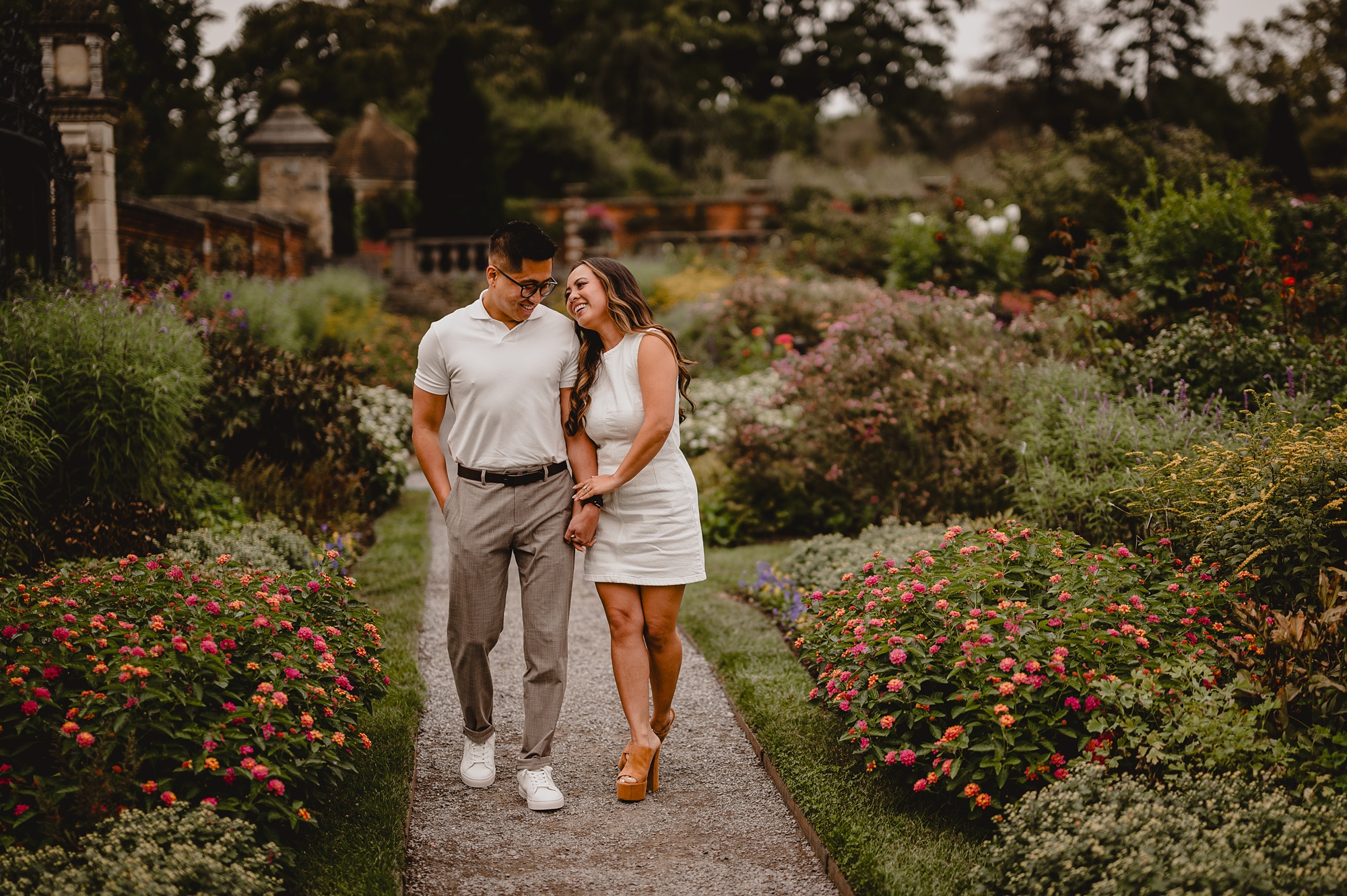 bride holds hands with man walking through Old Westbury Gardens