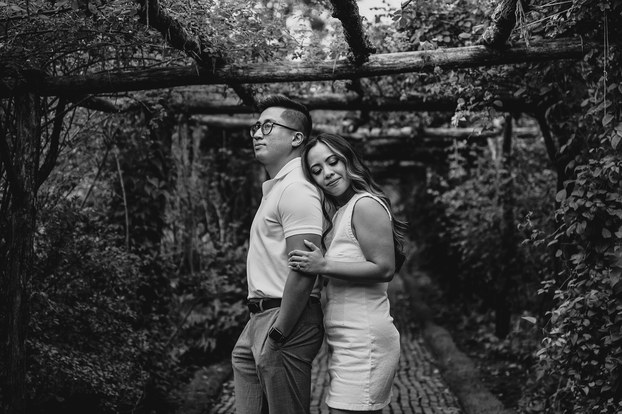 woman leans on man's back under wooden arbor 