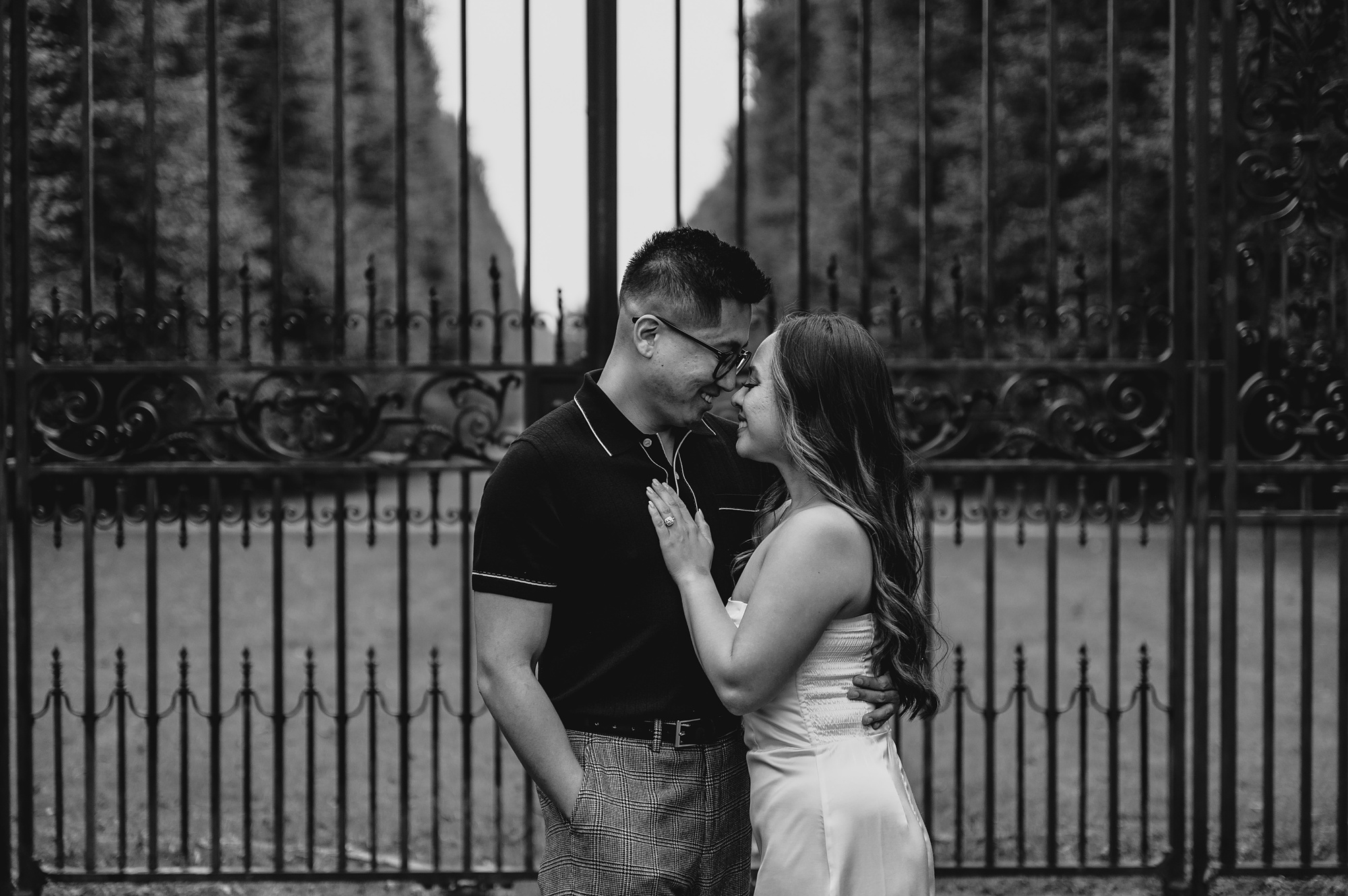 woman leans into man in front of wrought iron gate at Old Westbury Gardens