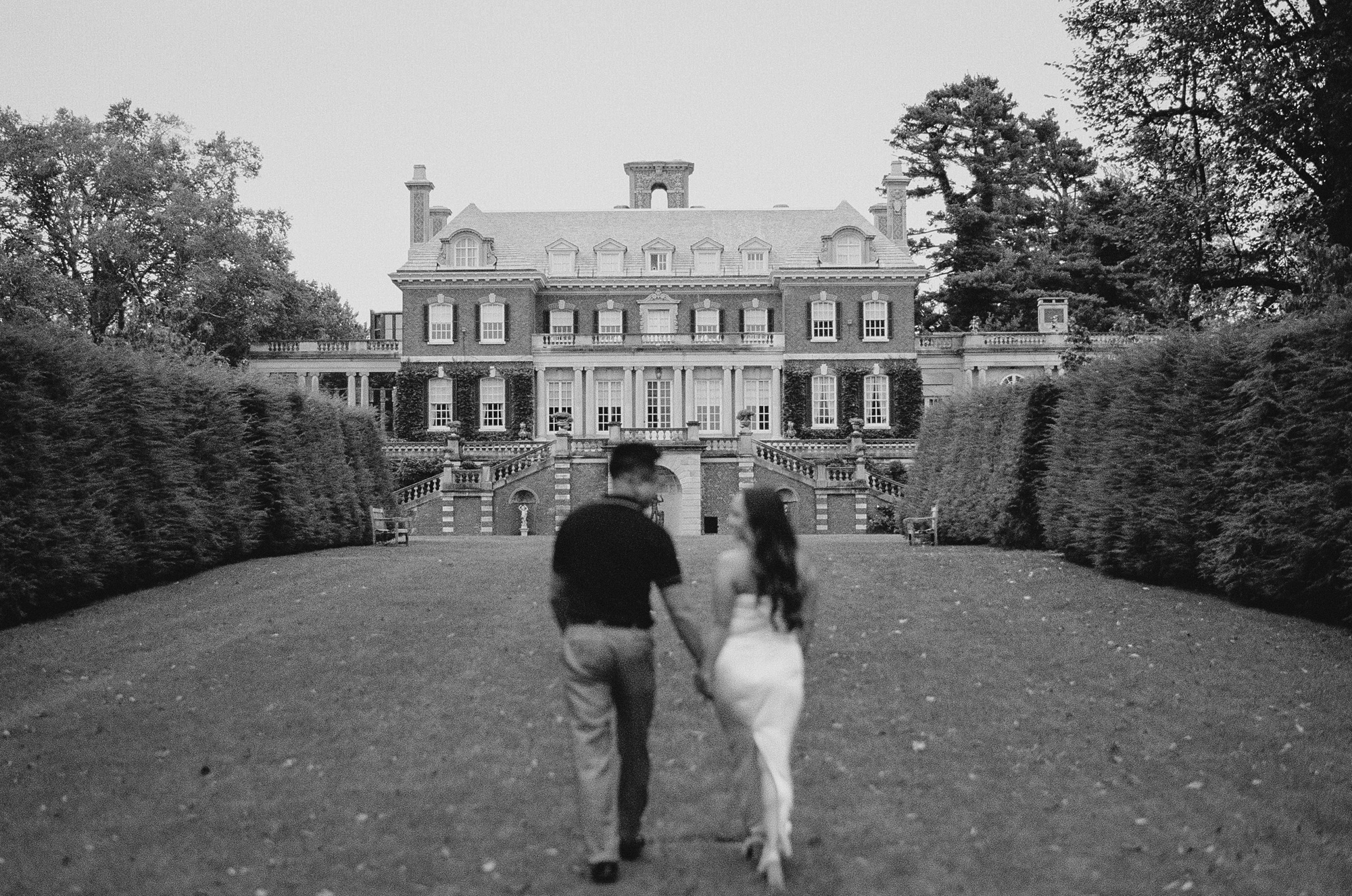 man and woman walk towards mansion on grounds at Old Westbury Gardens