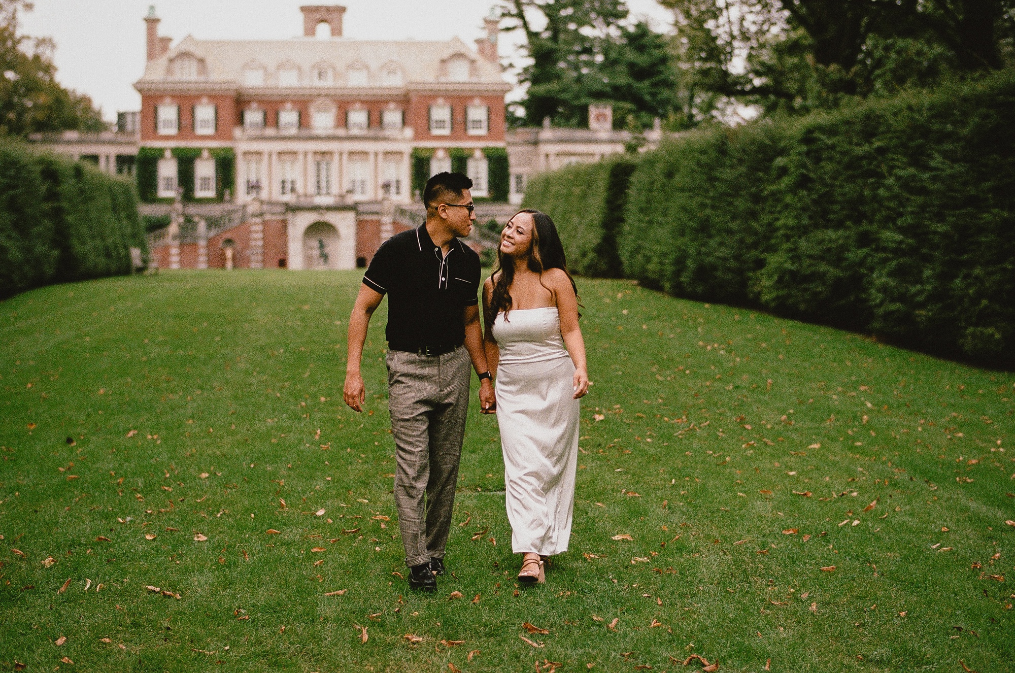 engaged couple holds hands on lawn at Old Westbury Gardens
