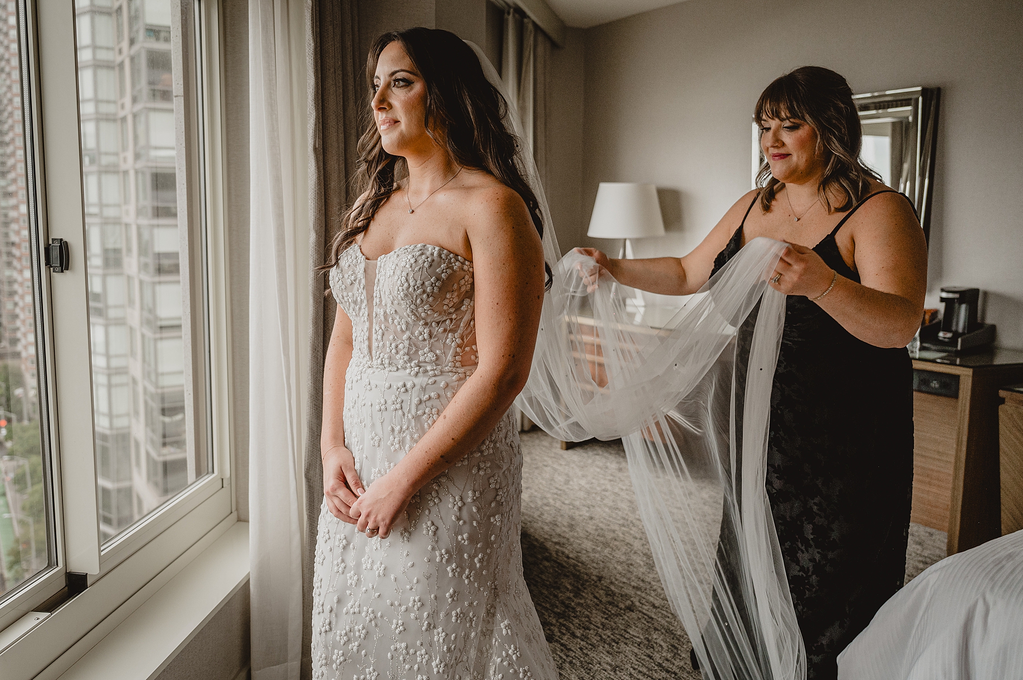 bridesmaid holds out veil for bride on morning of wedding in Jersey City