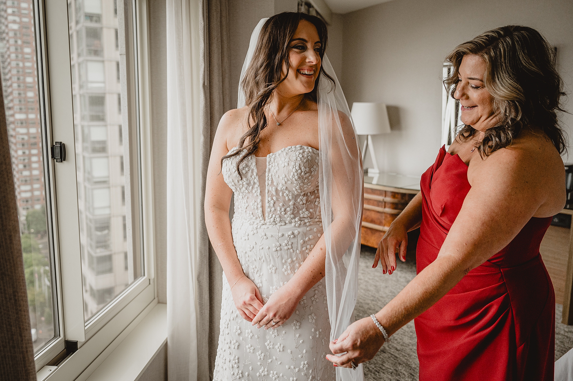 mother helps bride with veil on morning of wedding in Jersey City hotel
