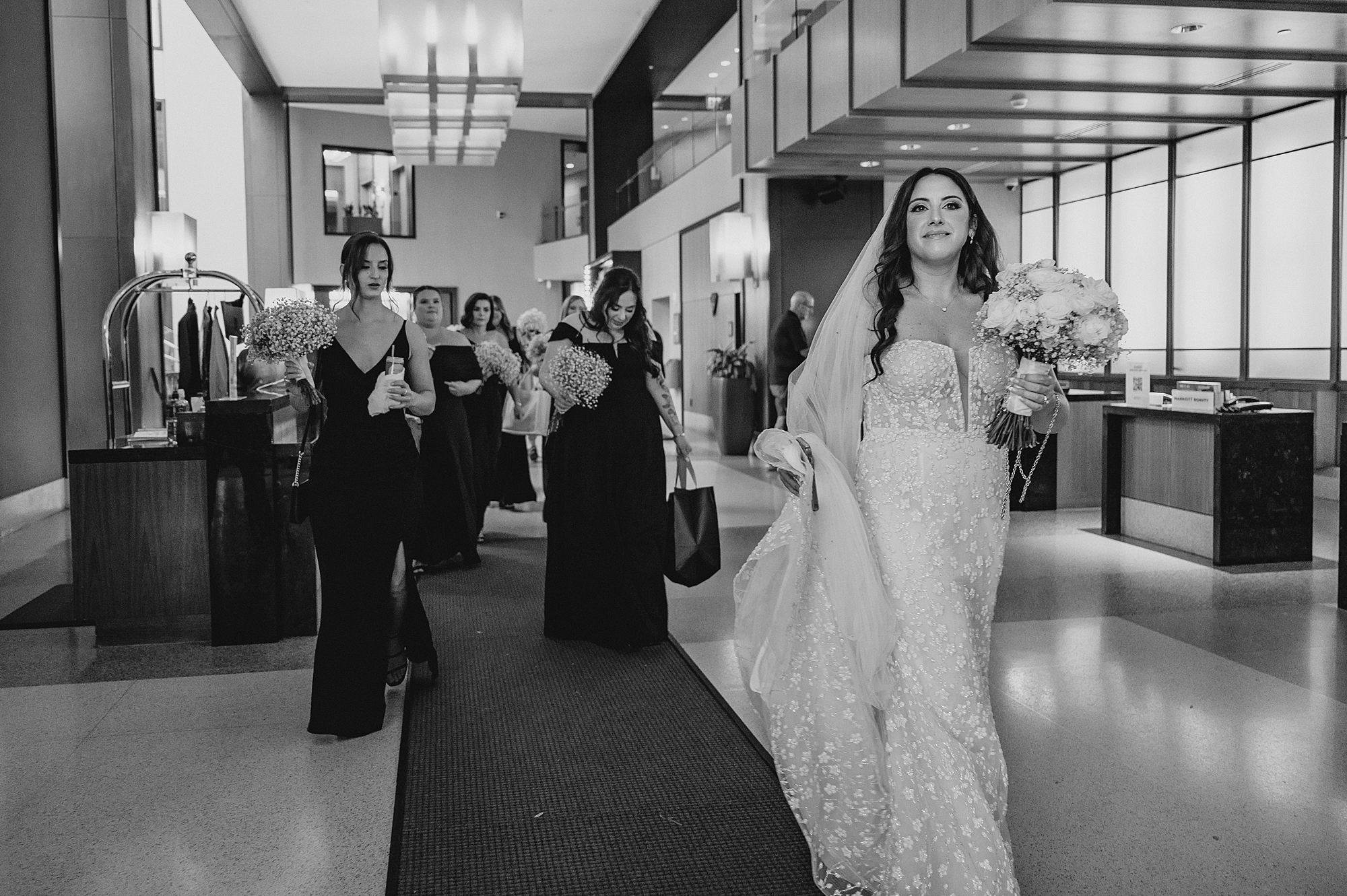 bridesmaids walk behind bride through lobby of Jersey City hotel