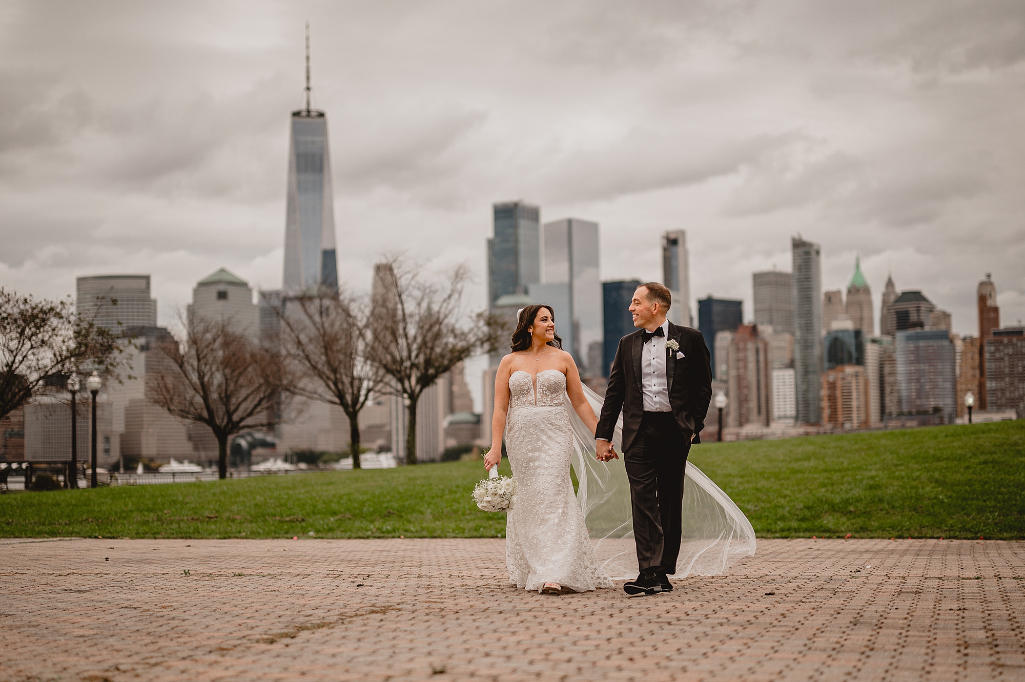 bride and groom hold hands walking on brick pathway outside the Liberty House