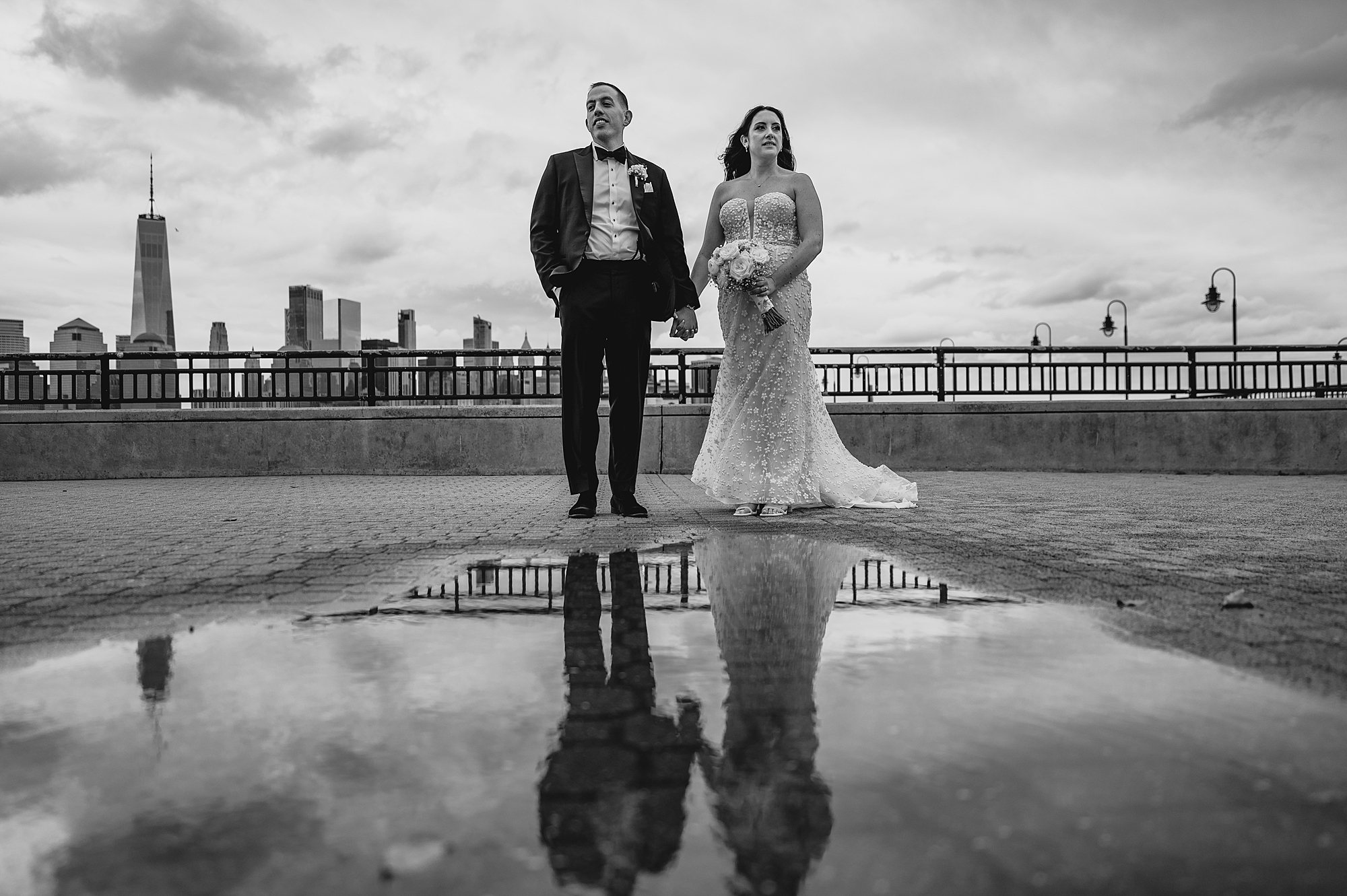 bride and groom hold hands with reflection in puddle of water