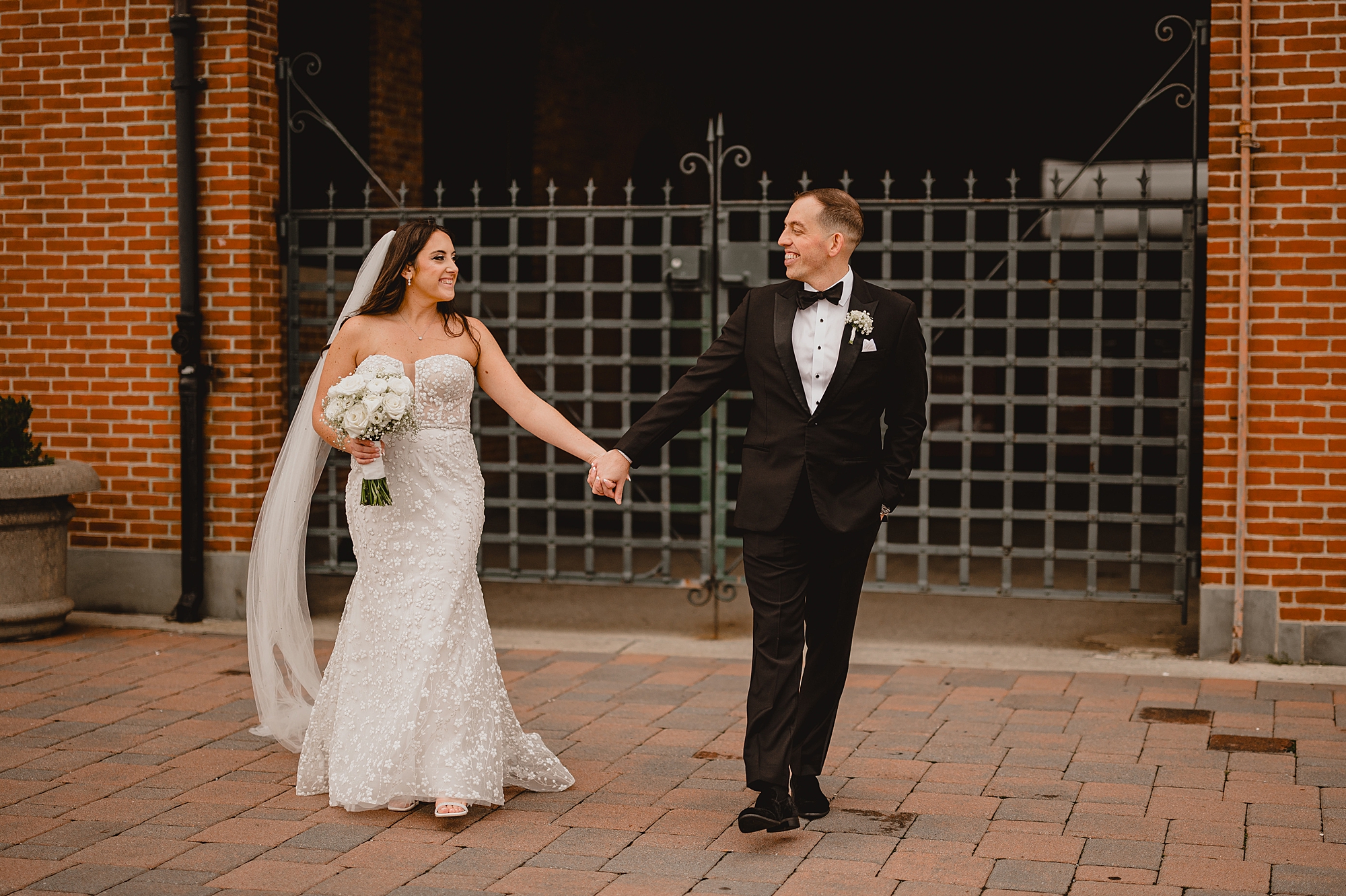 groom leads bride alongside the wall at the Liberty House