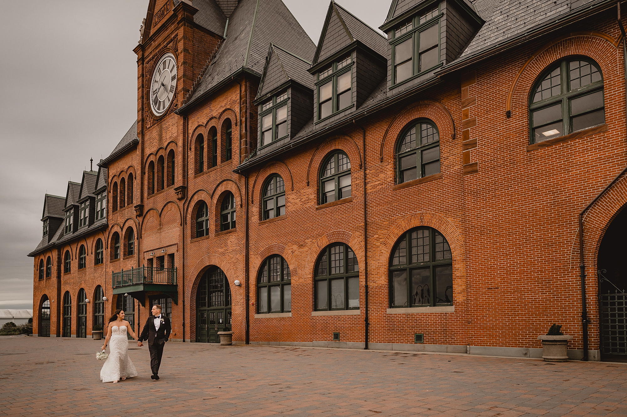 bride and groom hold hands walking in front of the Liberty House