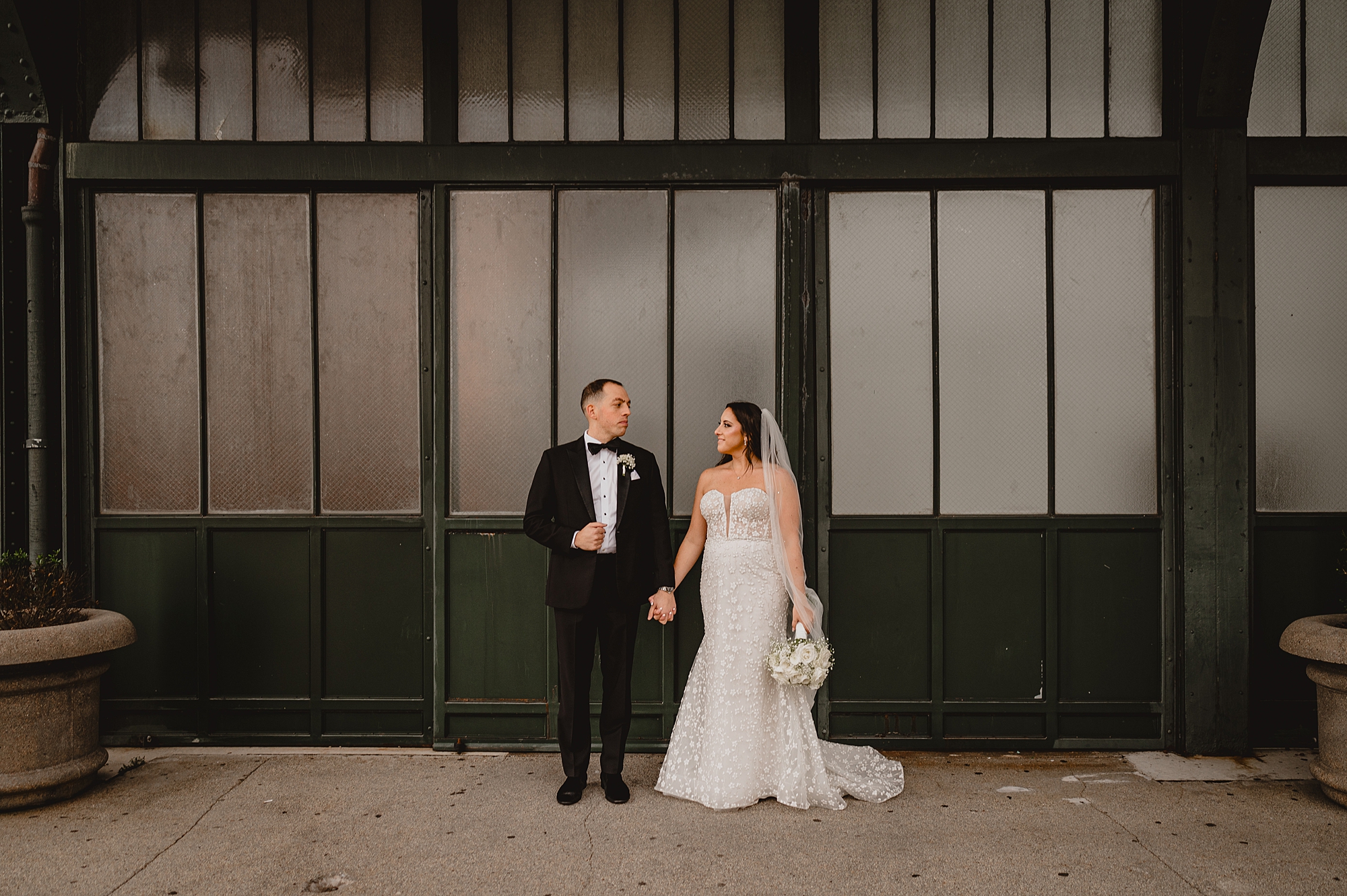 newlyweds smile at each other in front of windows at the Liberty House