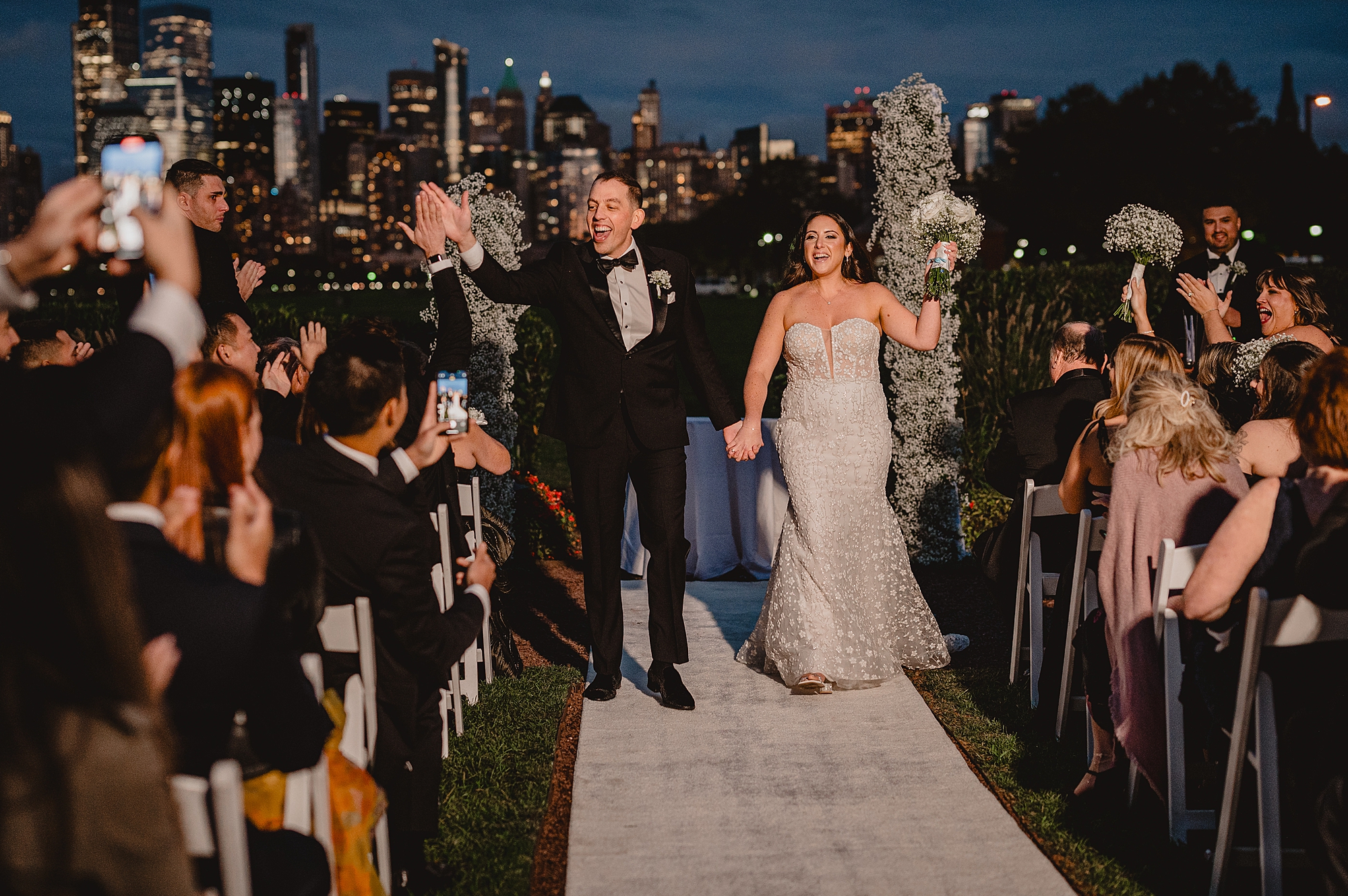 newlyweds cheer walking up aisle after sunset wedding ceremony at the Liberty House