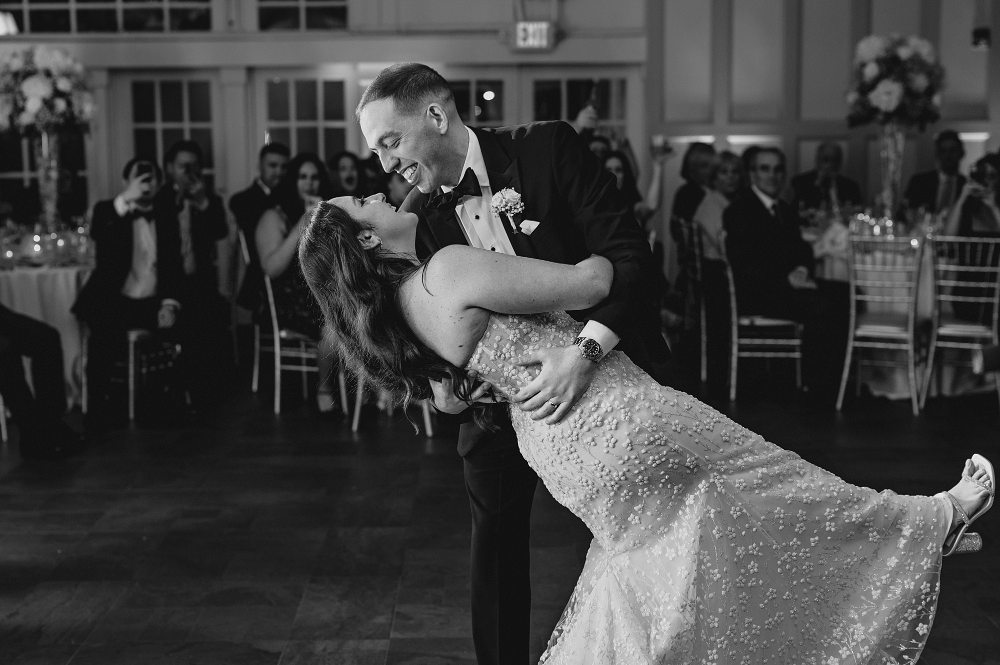 groom grins at bride during dip in first dance