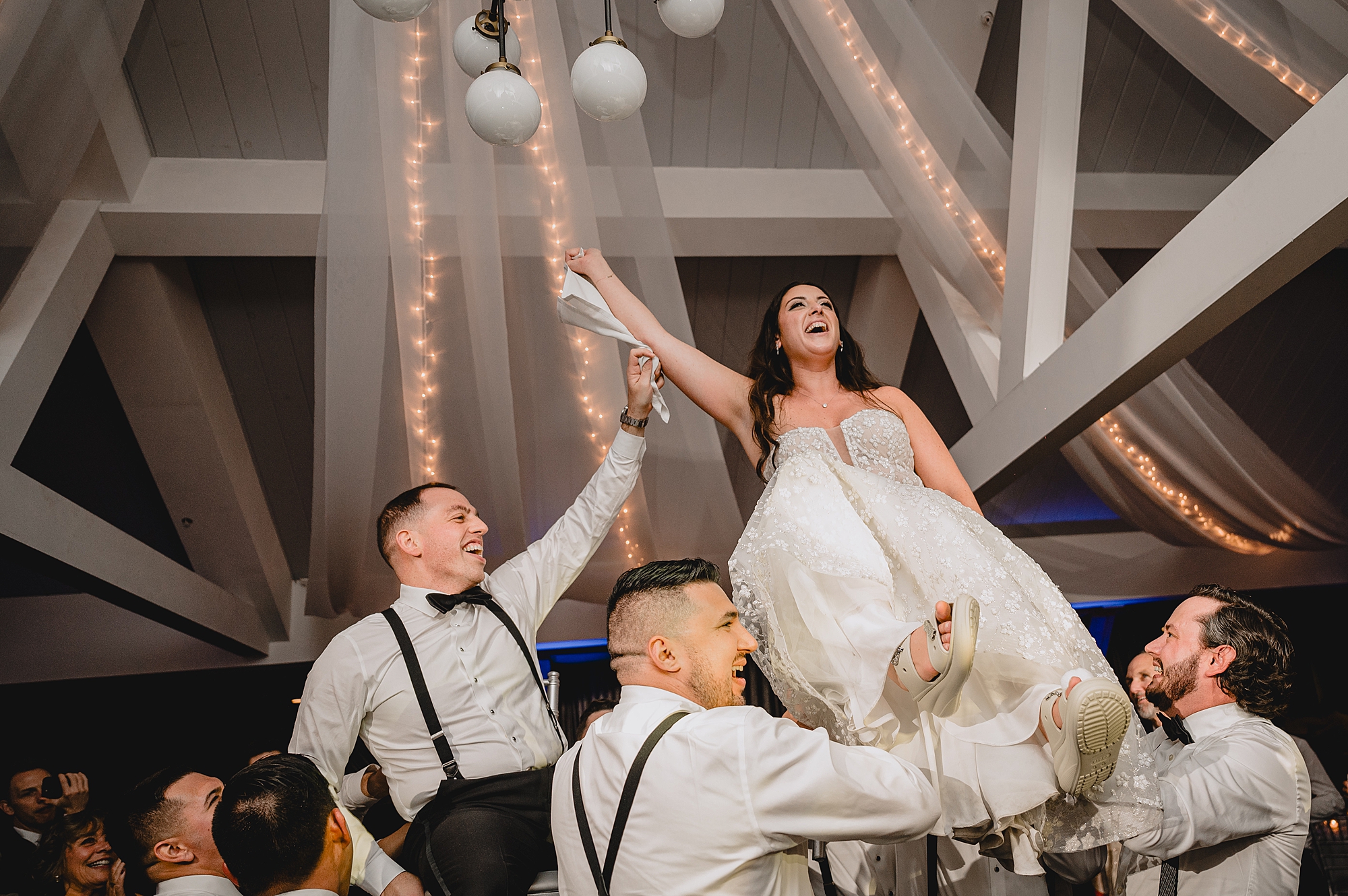 wedding guests lift up bride and groom during hora at the Liberty House wedding reception