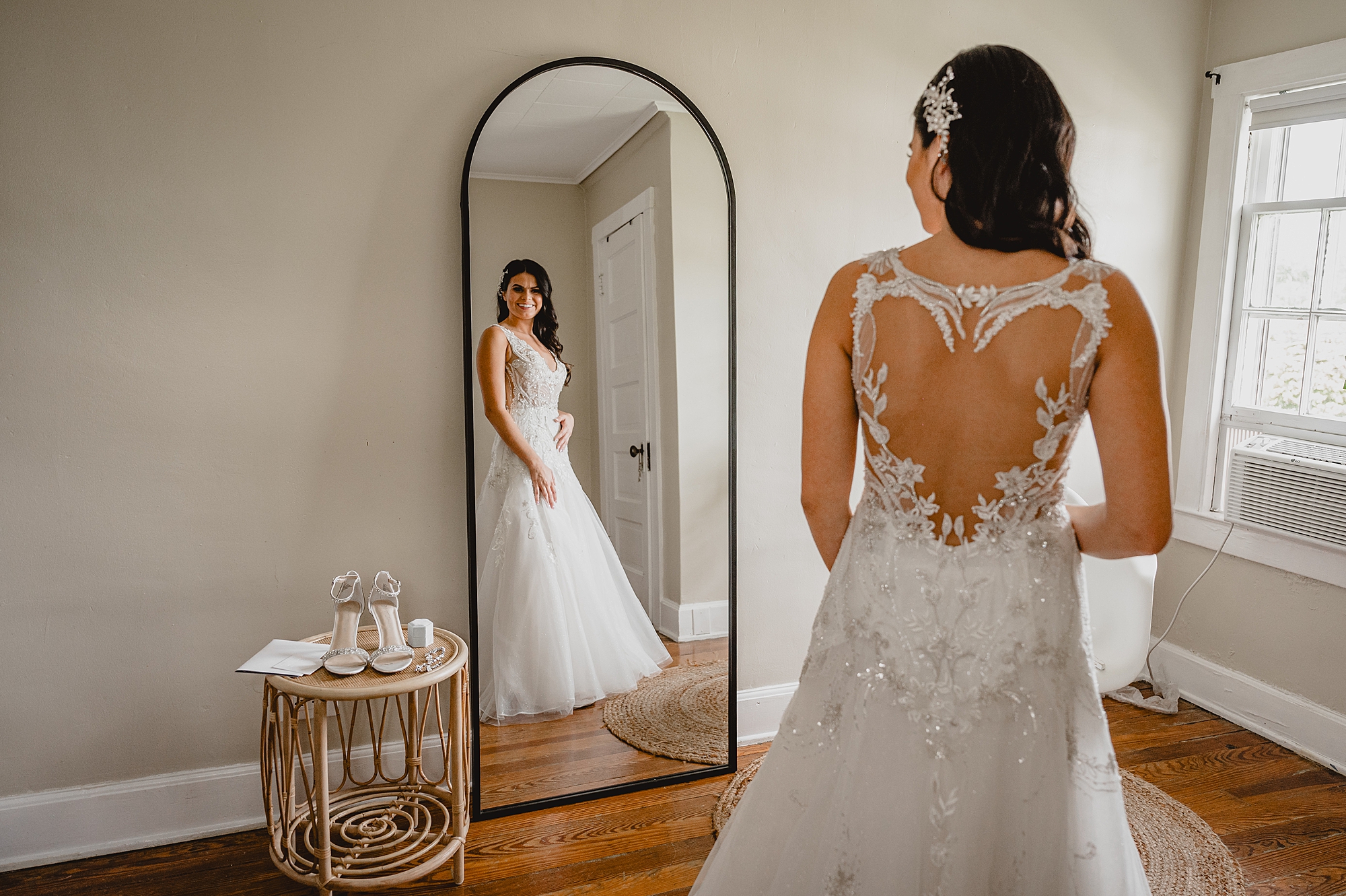 bride looks at herself in mirror with lace detailing on dress