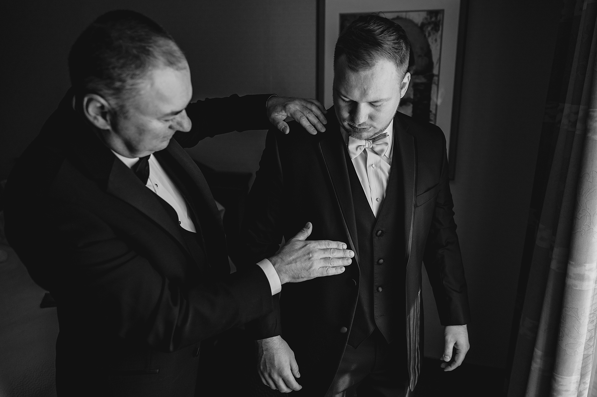 groomsman pats groom's lap during prep for NY wedding