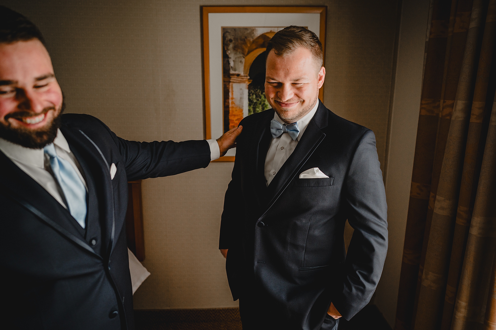 groomsman pats groom's shoulder during prep for NY wedding