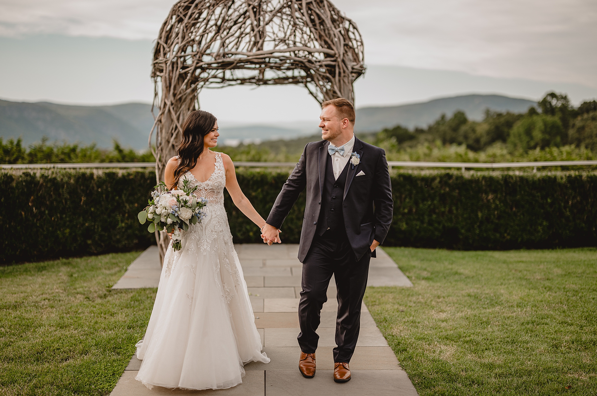 bride and groom hold hands walking in front of gazebo at the Garrison