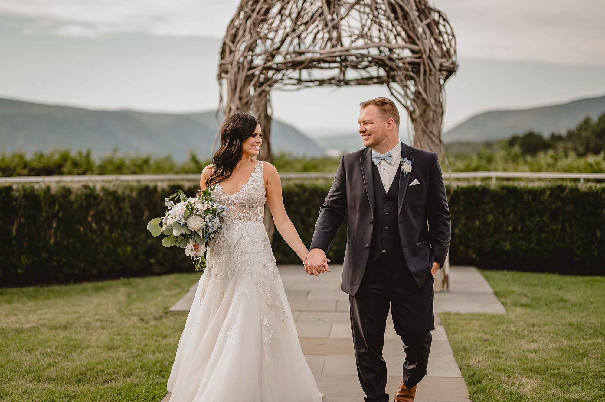 newlyweds hold hands walking in front of gazebo at the Garrison