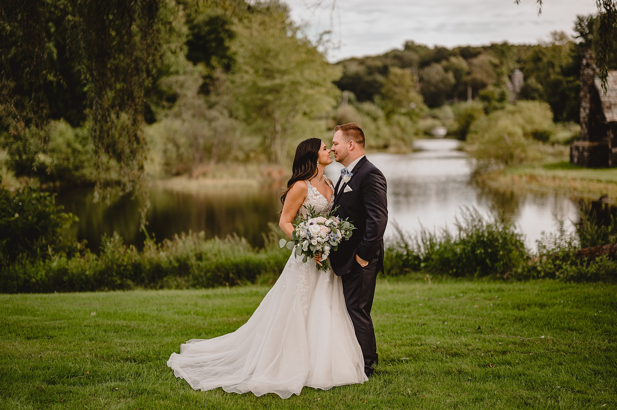 bride and groom kiss in front of pond at the Garrison in Hudson NY
