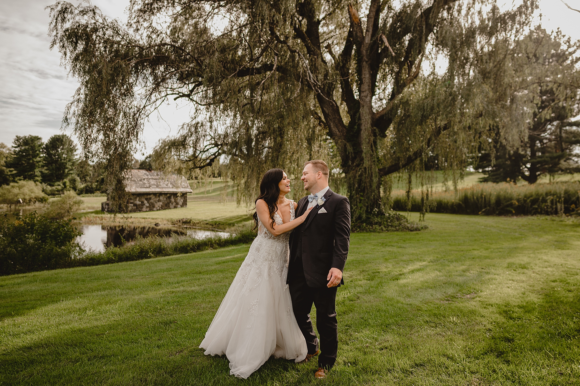 bride and groom hug under willow tree on farm at the Garrison