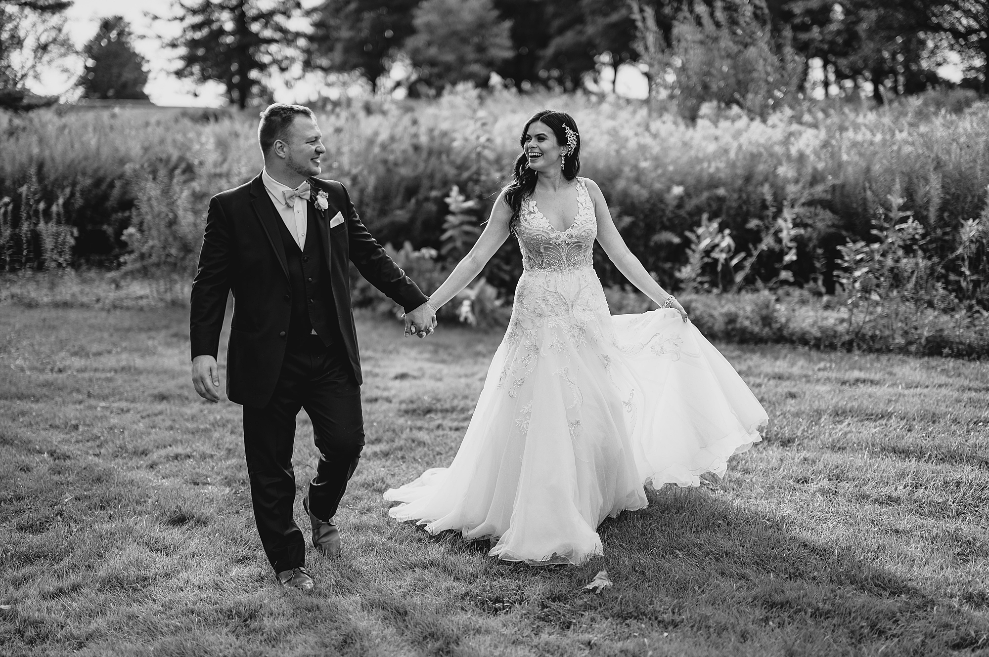 bride and groom hold hands walking on field at the Garrison