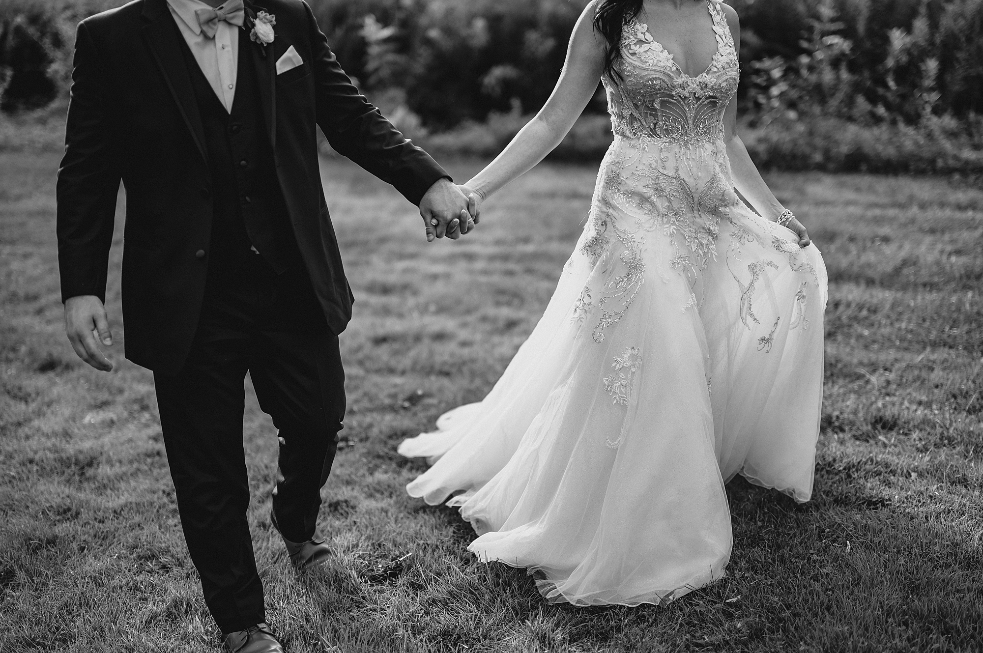 newlyweds hold hands walking across field at the Garrison in Hudson NY
