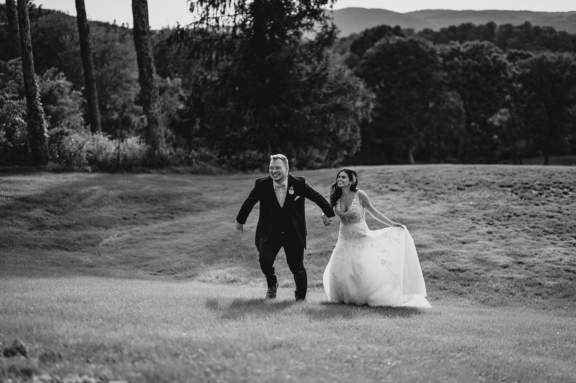 newlyweds hold hands running down hill at the Garrison