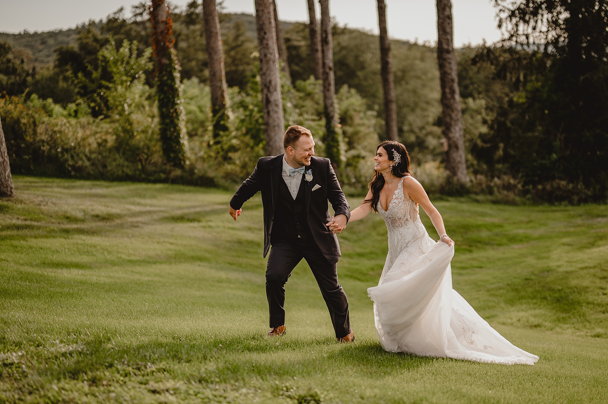 groom runs with bride across lawn in Hudson NY