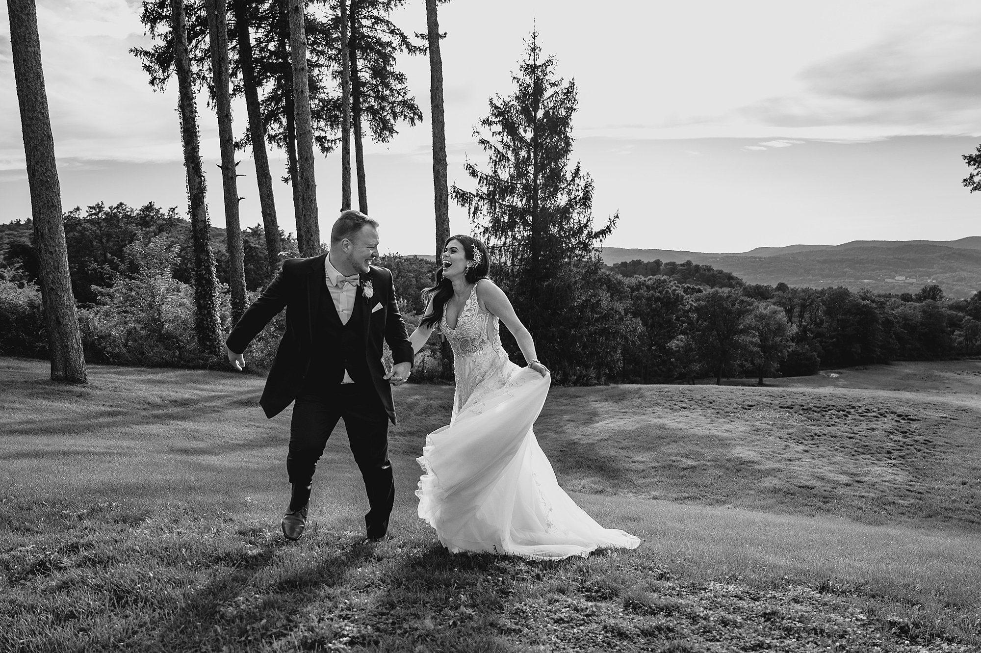 bride laughs while running with groom on lawn at the Garrison