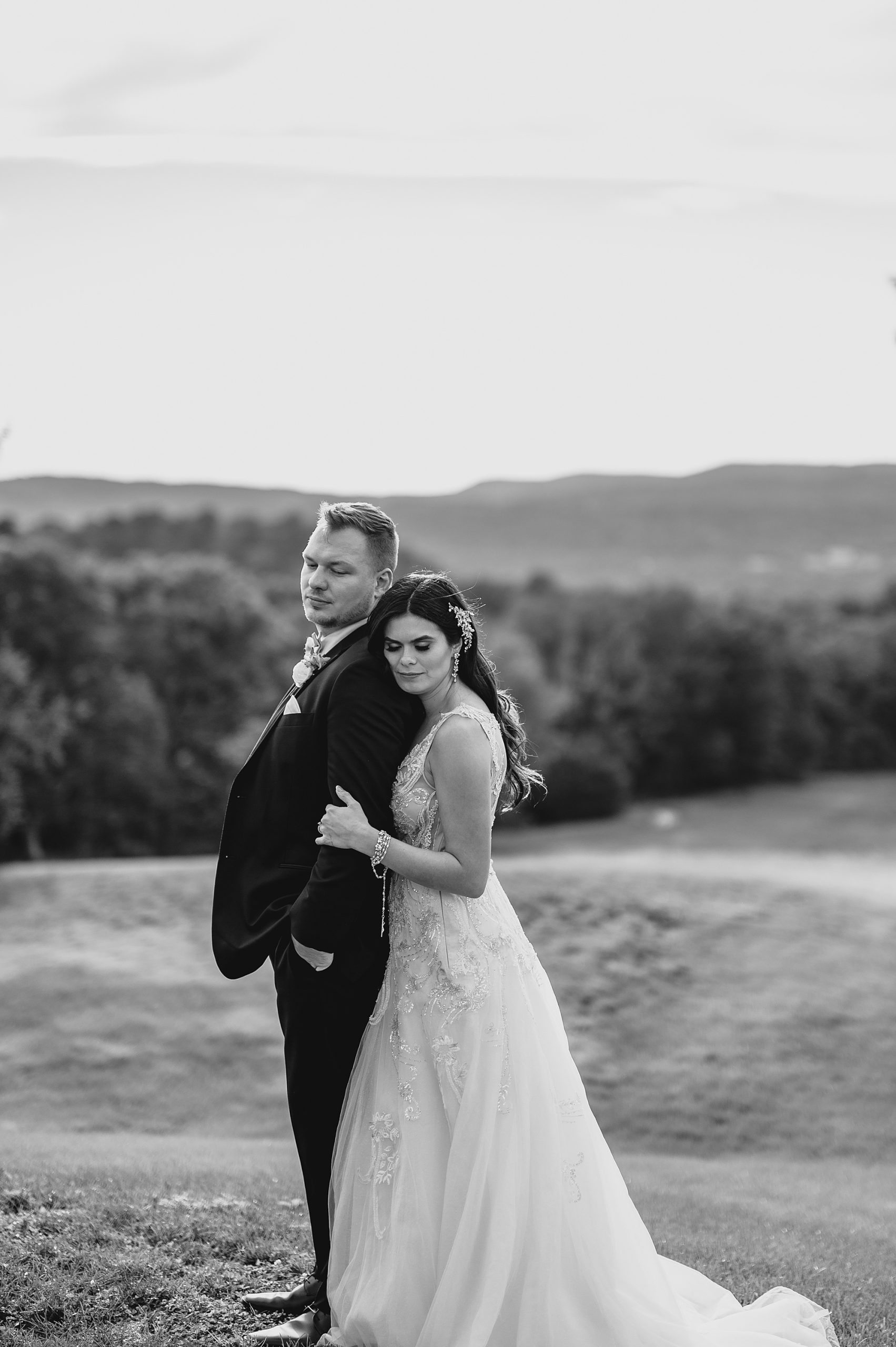 bride hugs groom from behind at the Garrison with mountains behind them