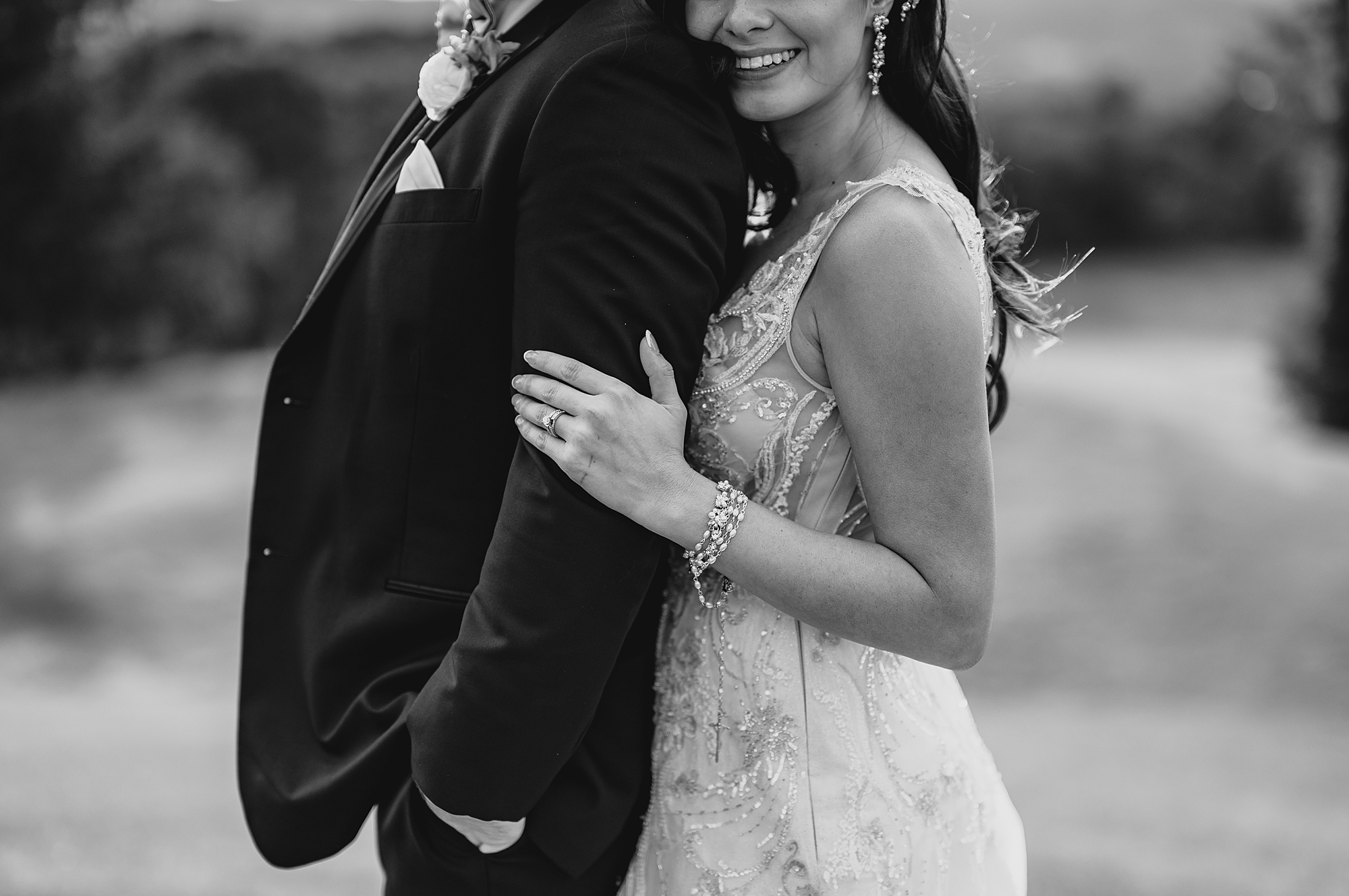 bride holds groom's arm hugging him from behind in Hudson NY