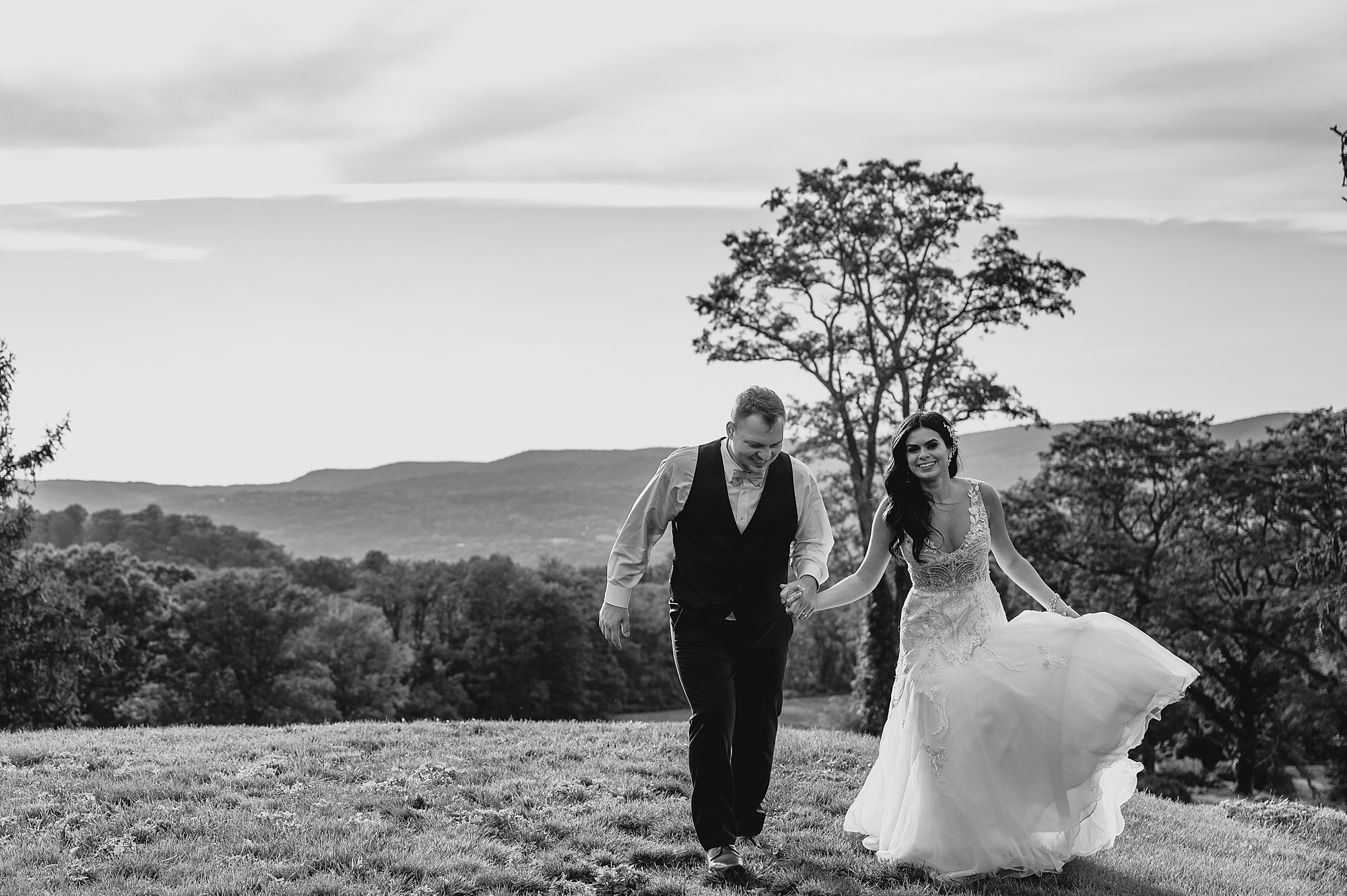 newlyweds hold hands walking away from oak tree in Hudson NY