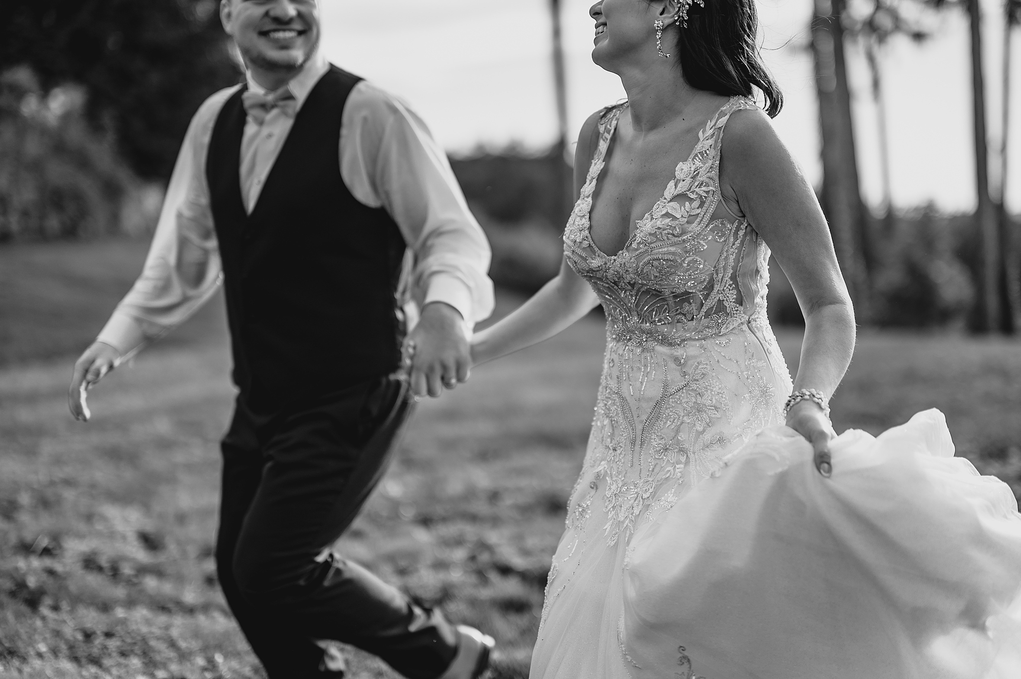 bride and groom hold hands while running across yard at the Garrison