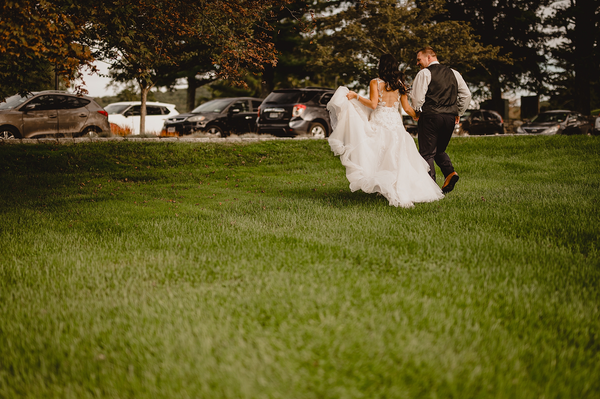 bride and groom run across grass together in New York